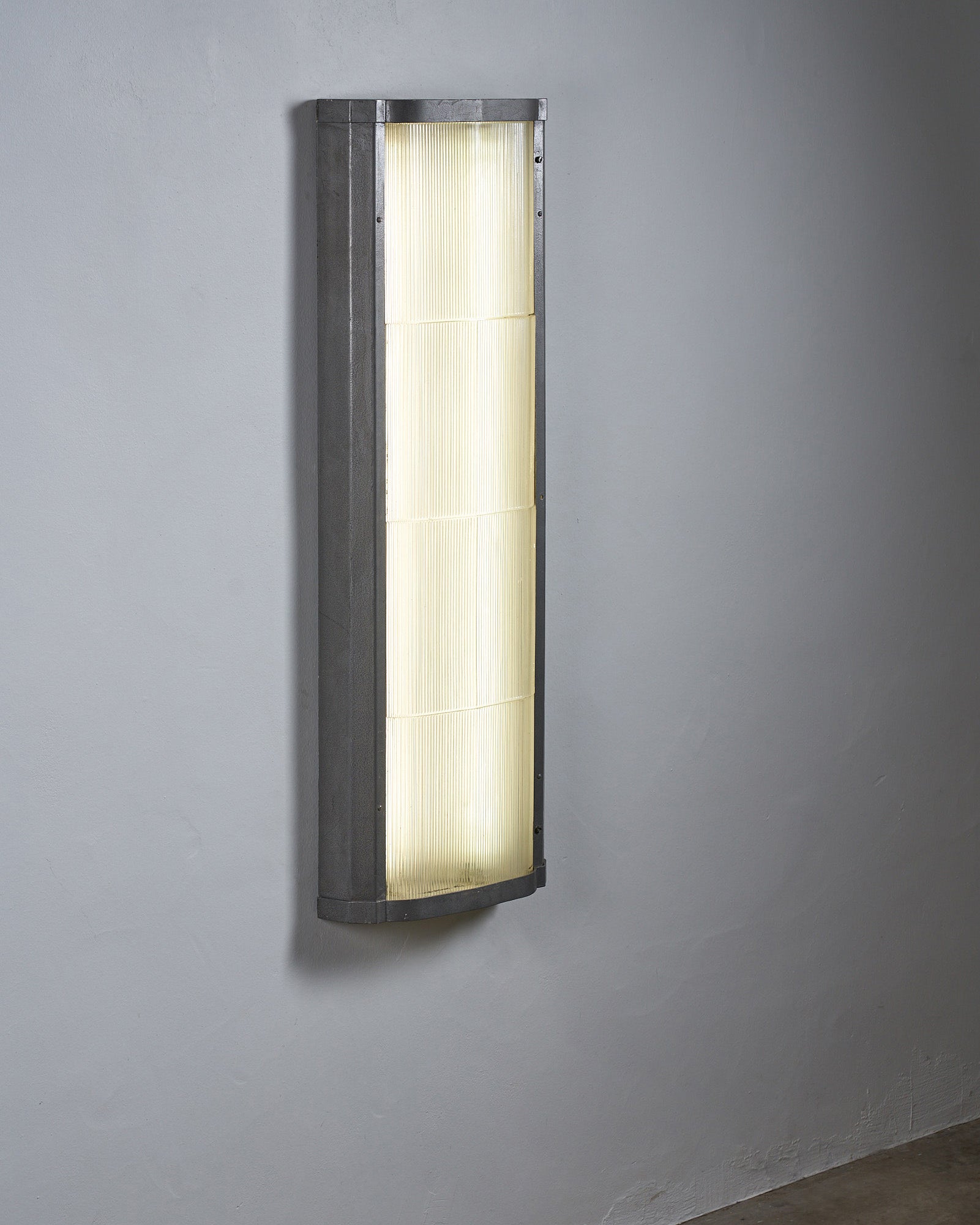 Industrial mount with glass diffuser providing illumination on a gray wall