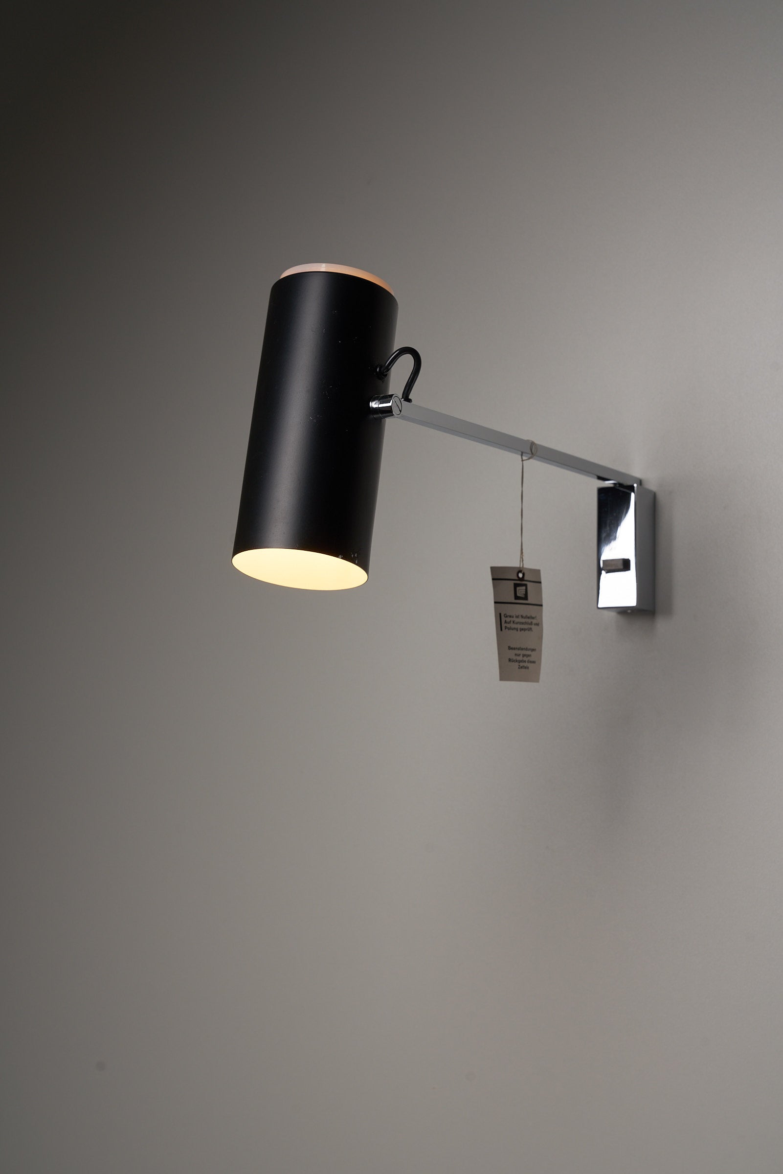 Directional Wall Spot by Cosack Leuchten with black metal shade, adjustable arm, and chrome wall mount providing customizable lighting.