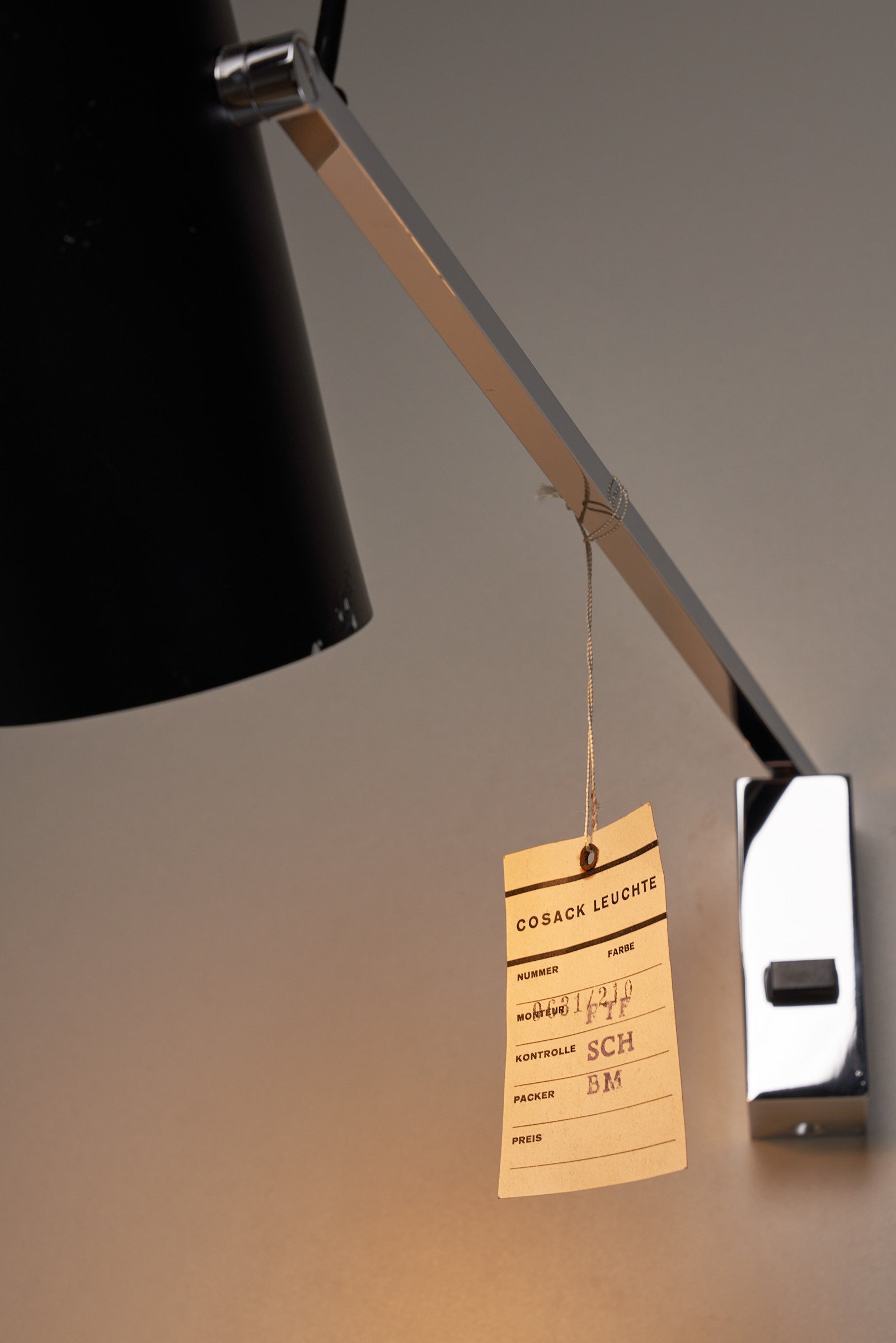 Directional Wall Spot with adjustable arm and black metal shade by Cosack Leuchten, featuring chrome wall mount and product tag