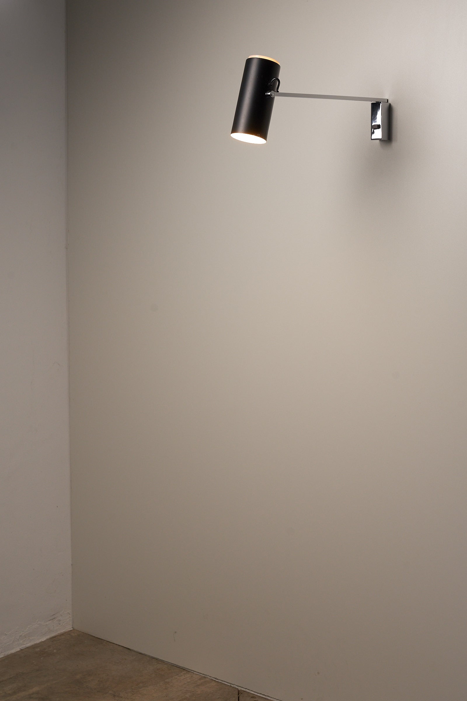 Directional Wall Spot by Cosack Leuchten with a chrome mount and pivoting black metal shade against a blank wall.