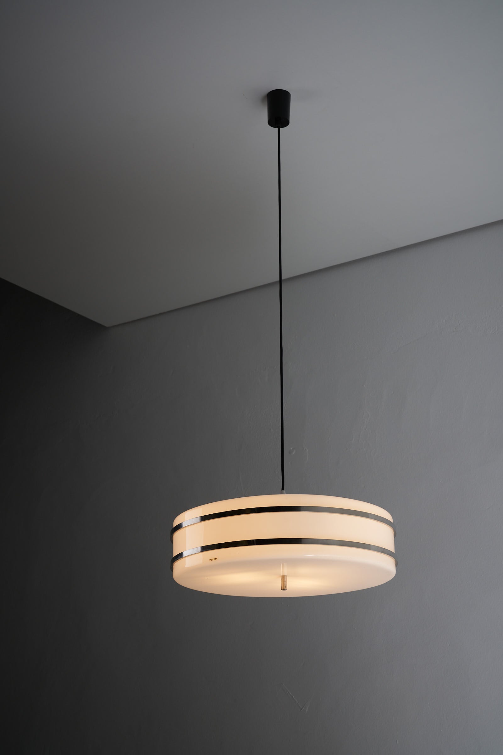 Circular pendant light by Stilux Milano with a flat cylindrical plexiglass form, chromed steel accents, and a repainted black exterior.