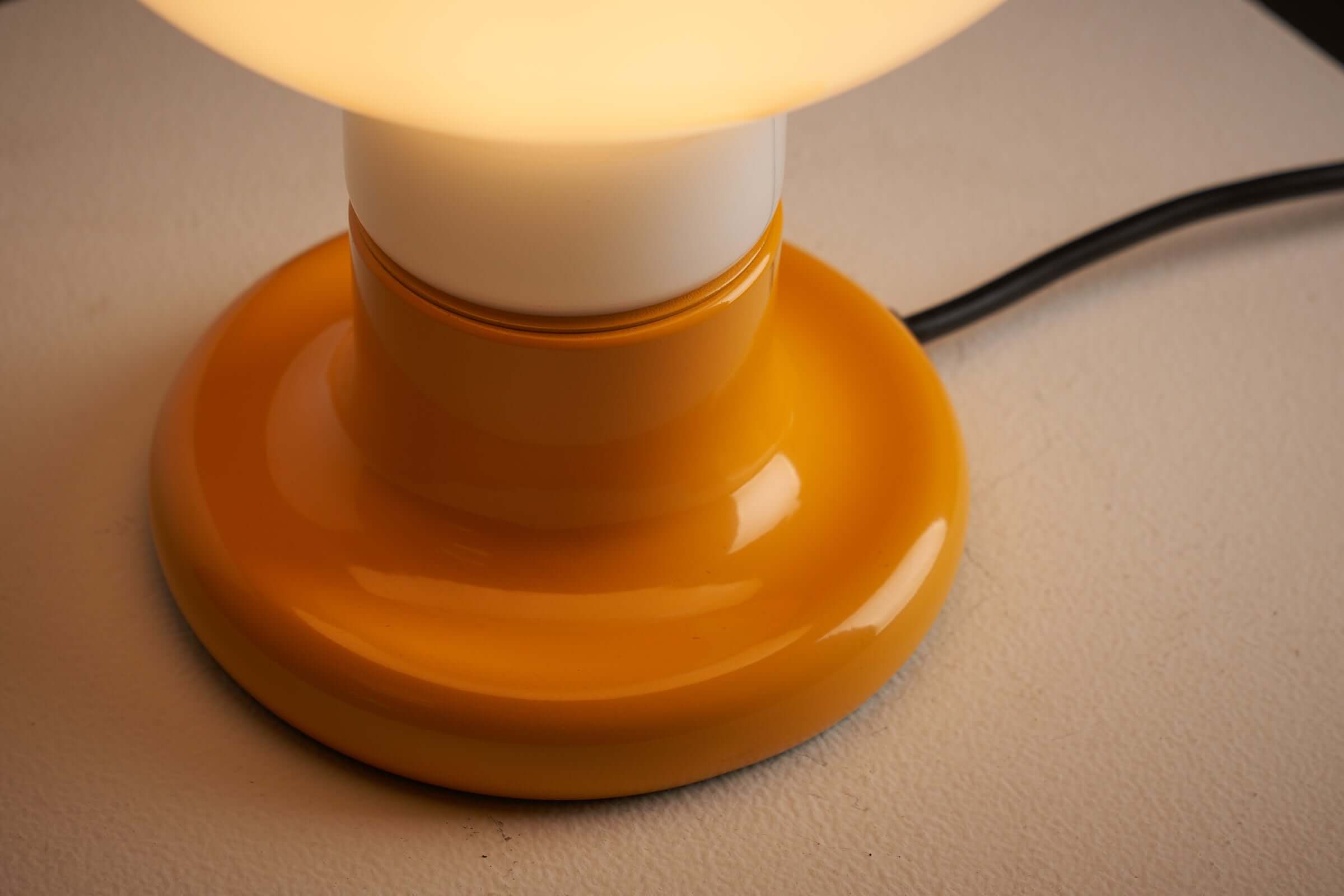 Yellow lacquered base of Cosack Leuchten table lamp with glowing milk glass sphere.