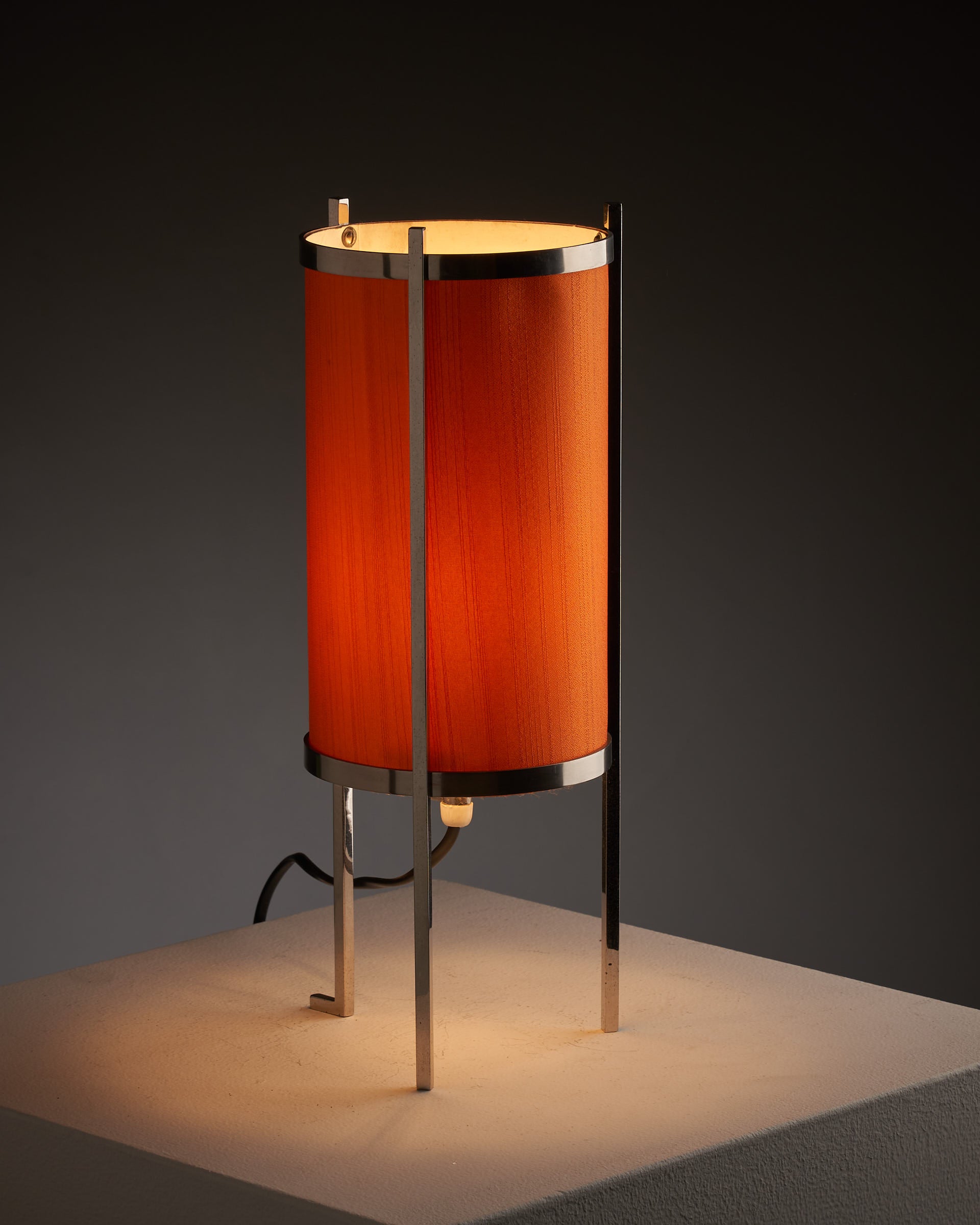 Modern chromed steel table lamp with orange cylindrical shade creating warm ambiance. Perfect for contemporary spaces.