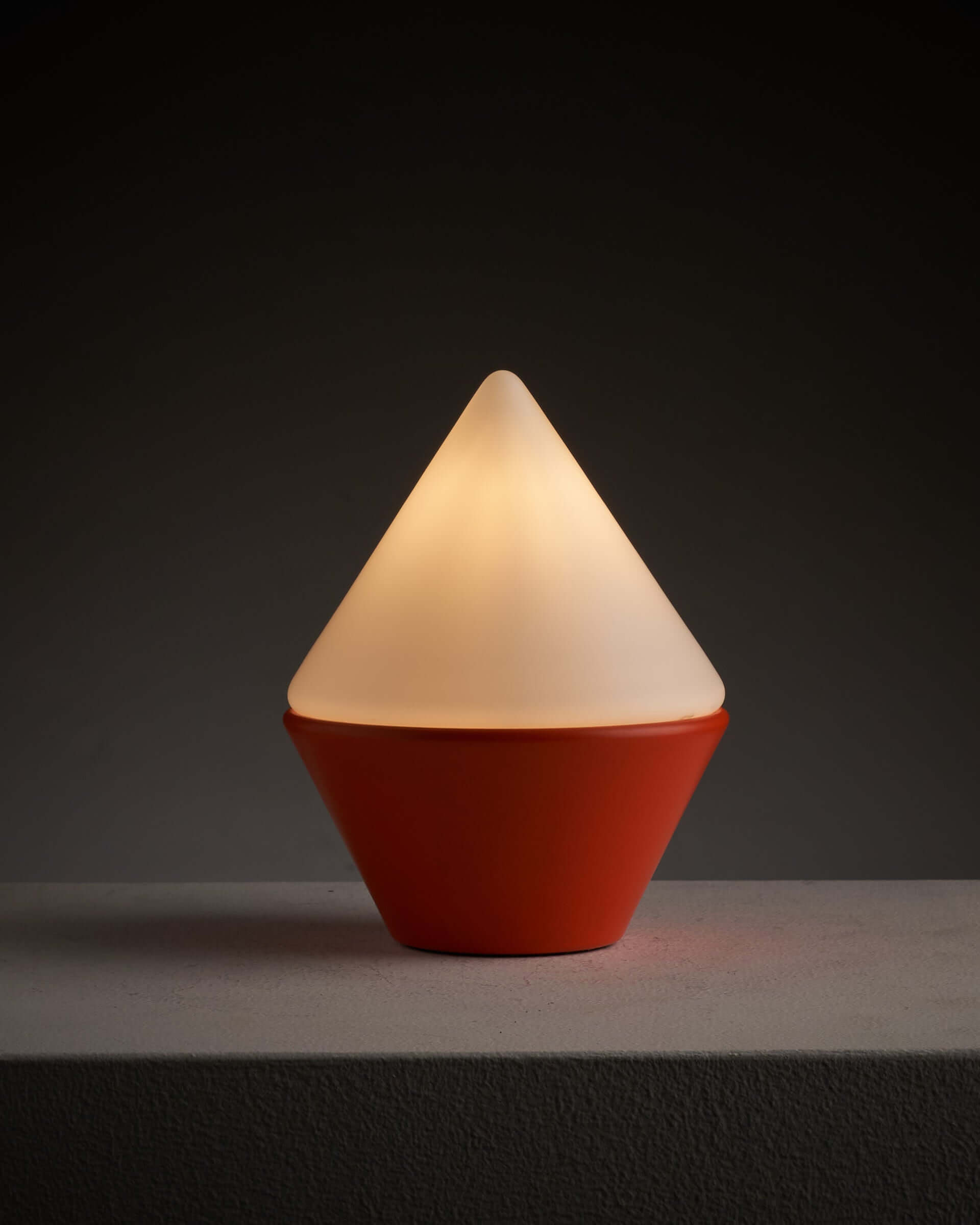 Cosack Leuchten table lamp with orange base and triangular opal glass shade, creating a soft inviting glow.