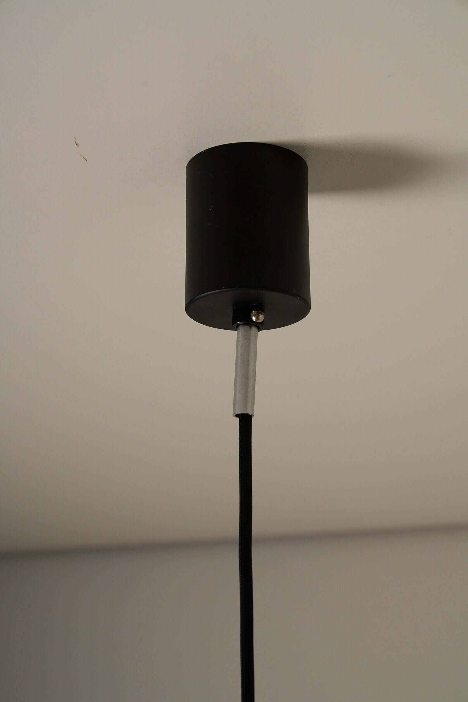 Cosack Leuchten 1960s black cylindrical pendant lamp with textured glass and spring connection viewed from below.