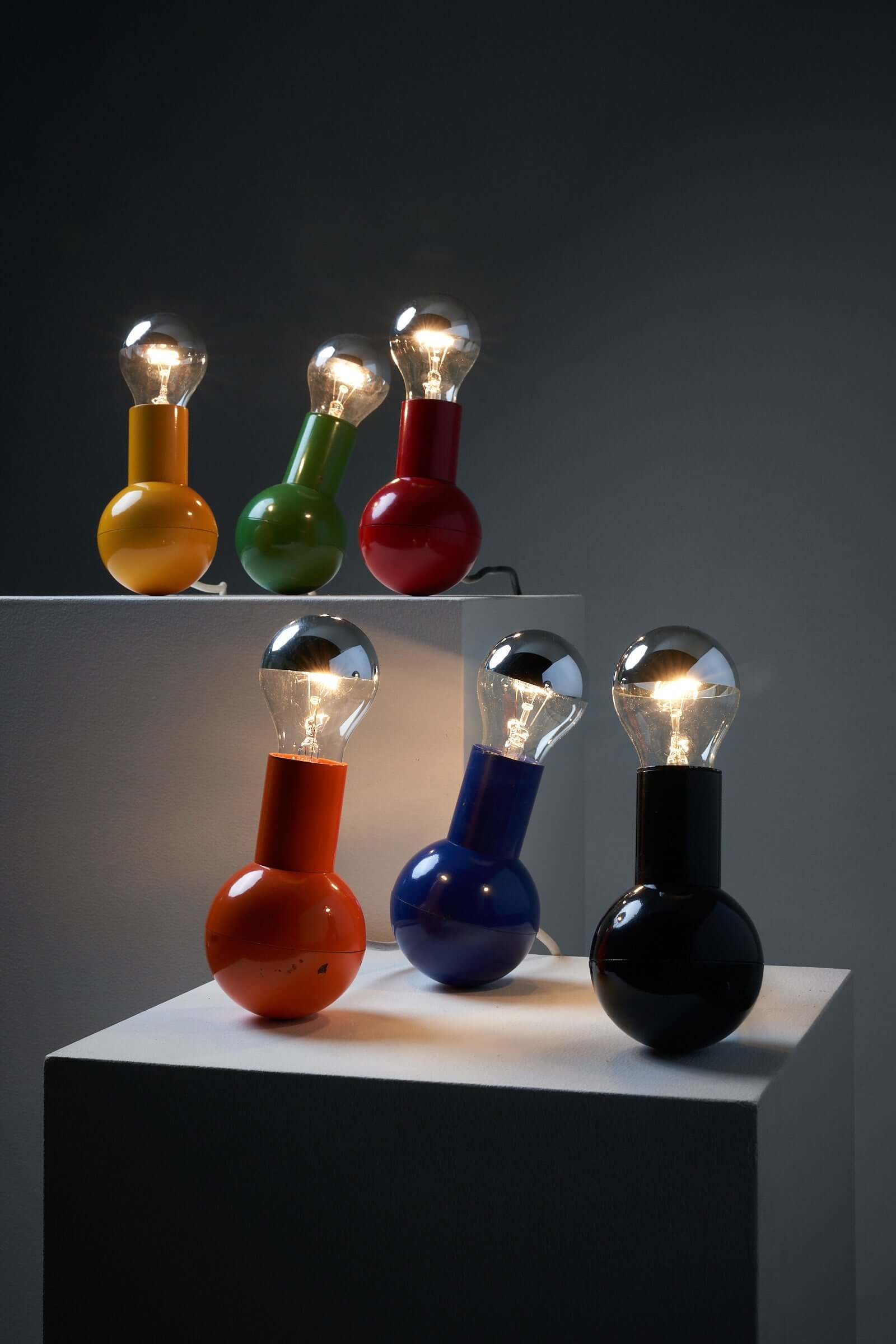 Vibrant Kugel table lamp collection by Cosack Leuchten in various colors displayed on pedestals, showcasing bulbous design and unique lighting.