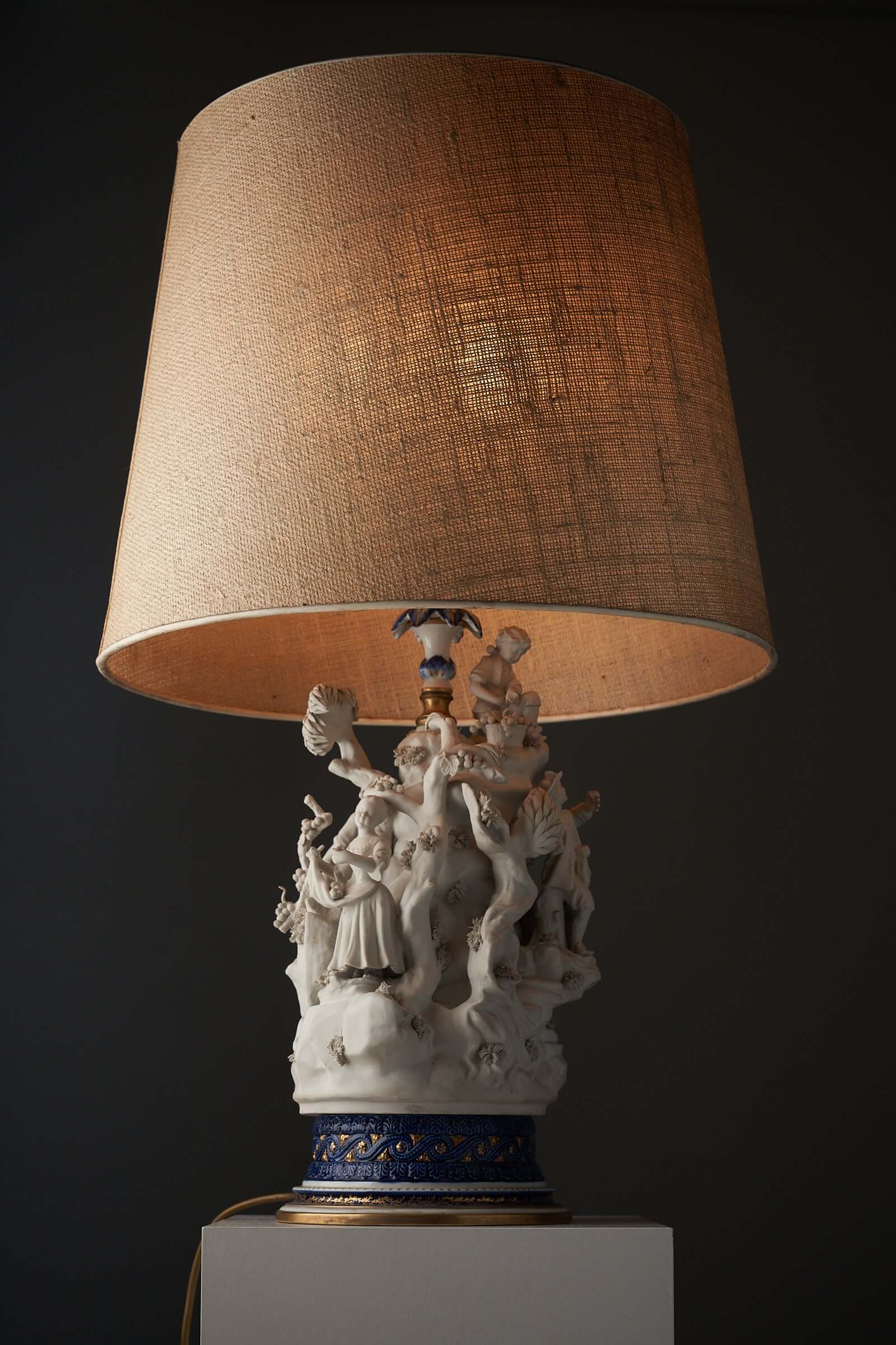 Porcelain table lamp with sculpted figurines by Mangani, 20th-century Italy on a cobalt blue base with gold accents.