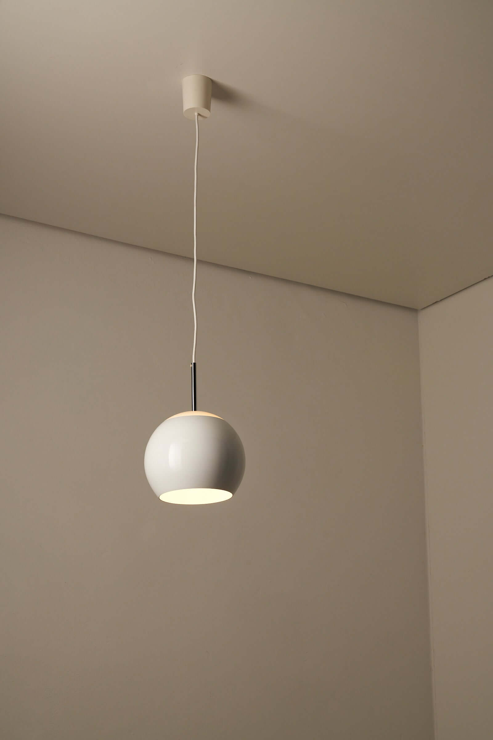 White sphere pendant lamp by Cosack with chrome stem, featuring a soft, glowing effect in a minimalist setting.