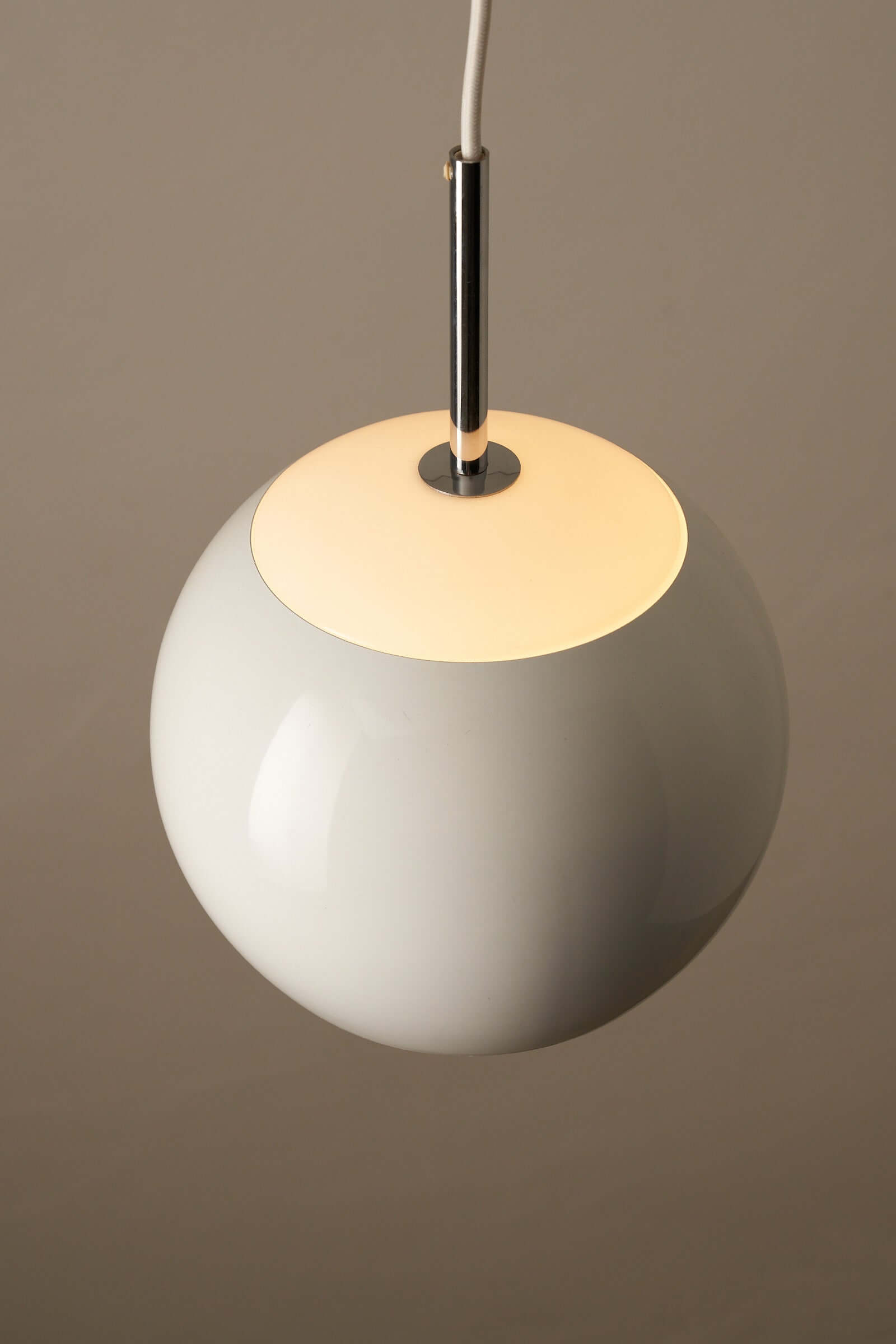 Elegant white sphere pendant lamp with chrome stem and opal top, showcasing mid-century design and soft illumination.