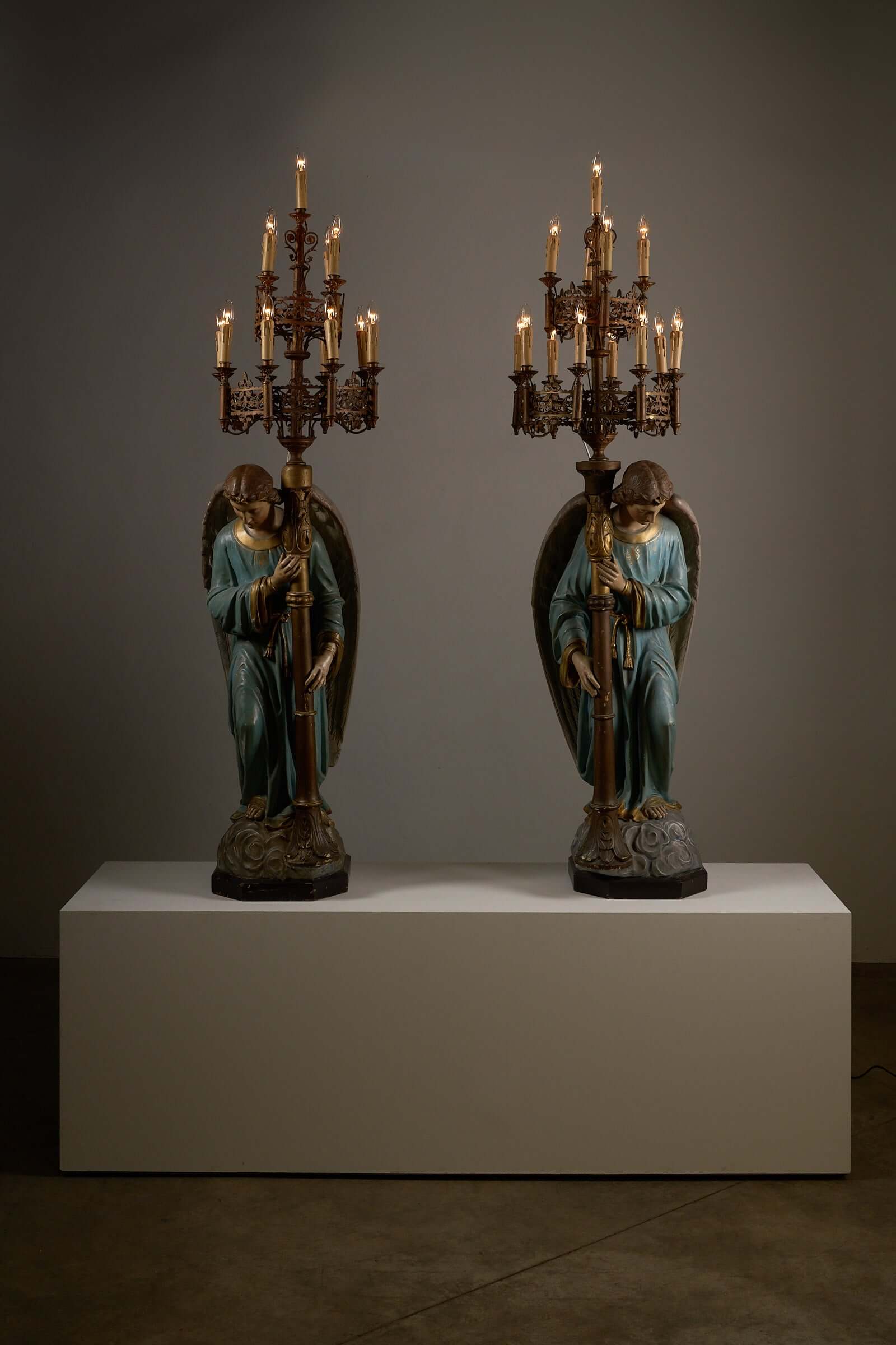 19th century kneeling angel candle holders with chandeliers on display