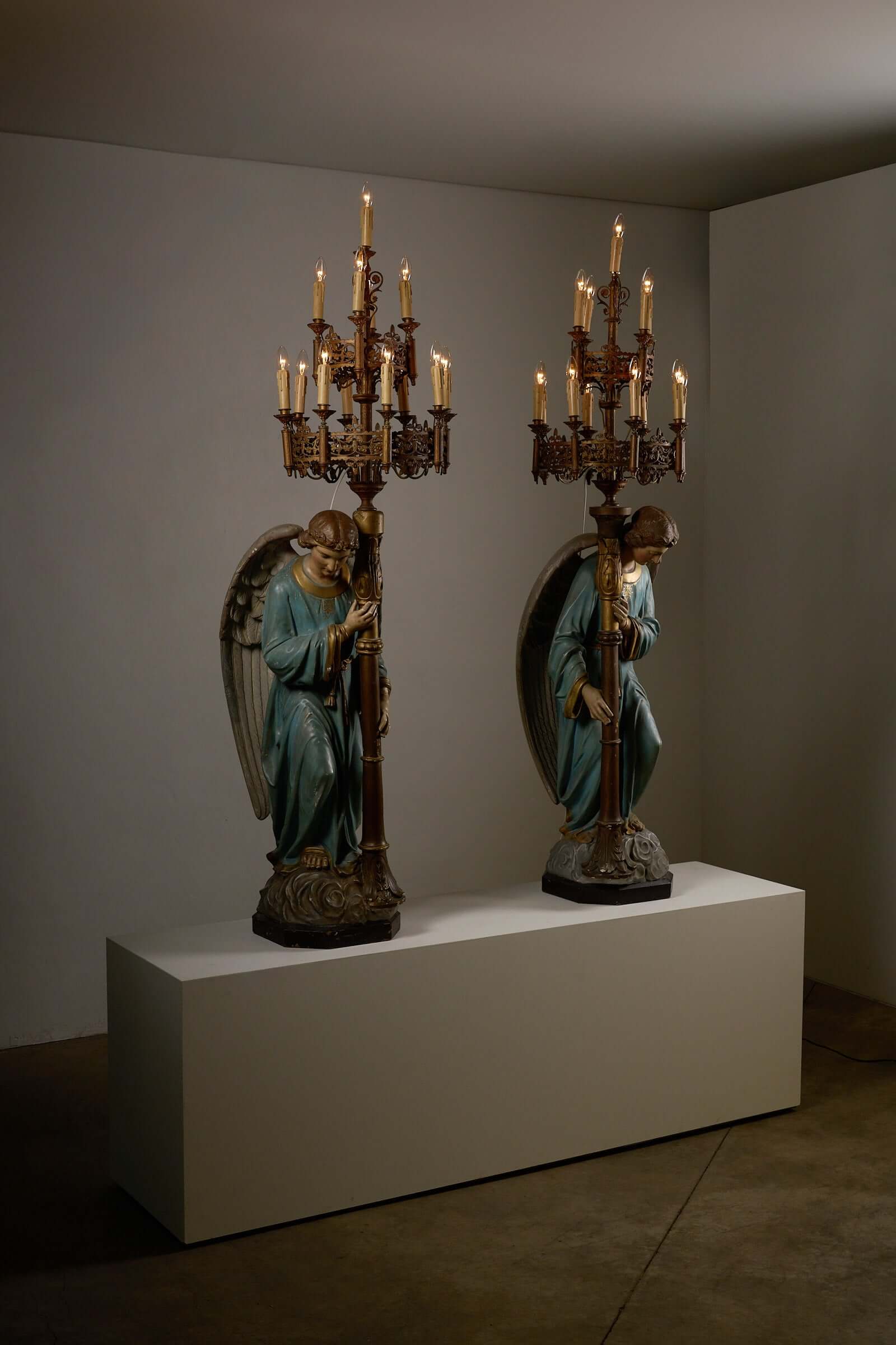 Pair of kneeling angel candle holders with 19th-century chandeliers and intricate ornaments on display