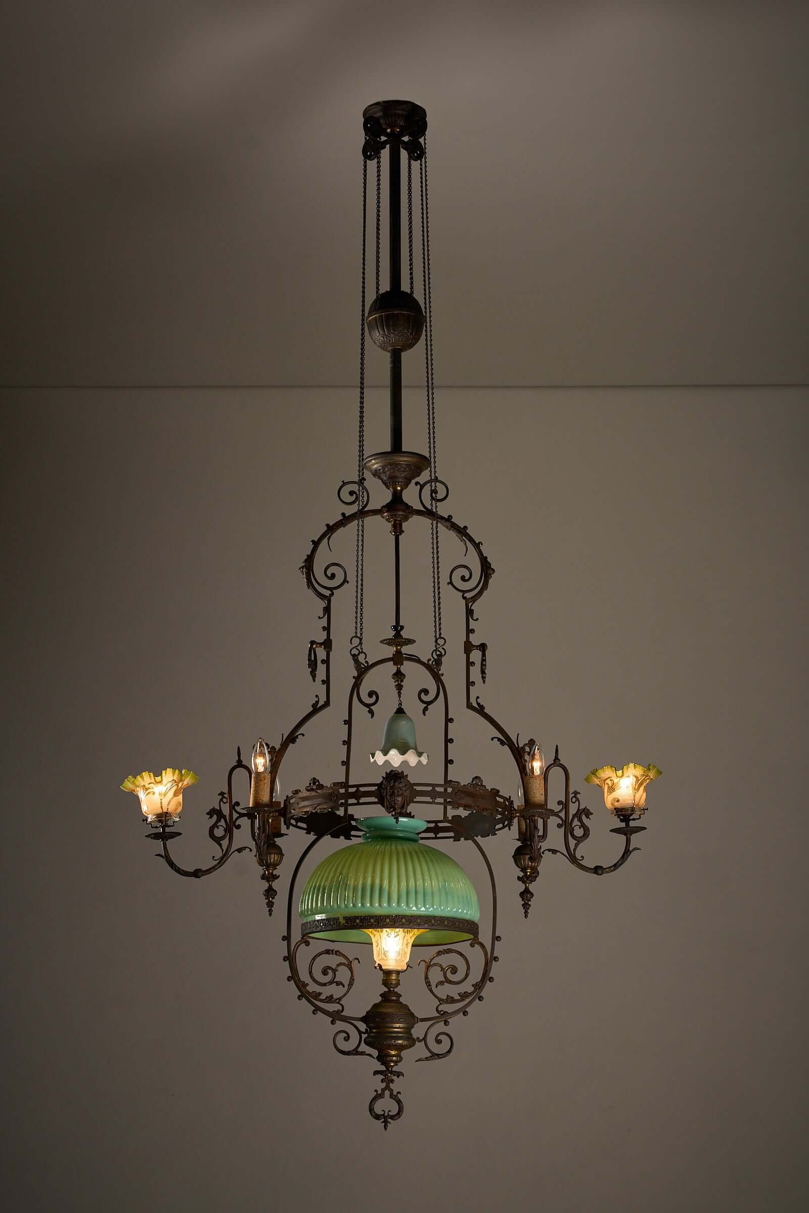 Antique adjustable height chandelier with original glasswork and brass detailing, featuring an elegant counterweight system.