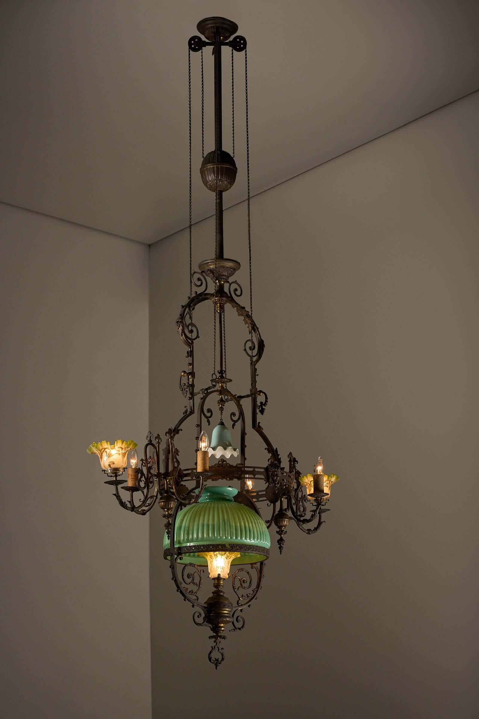 Antique adjustable height chandelier with original glasswork and brass detailing, featuring an elegant counterweight system.