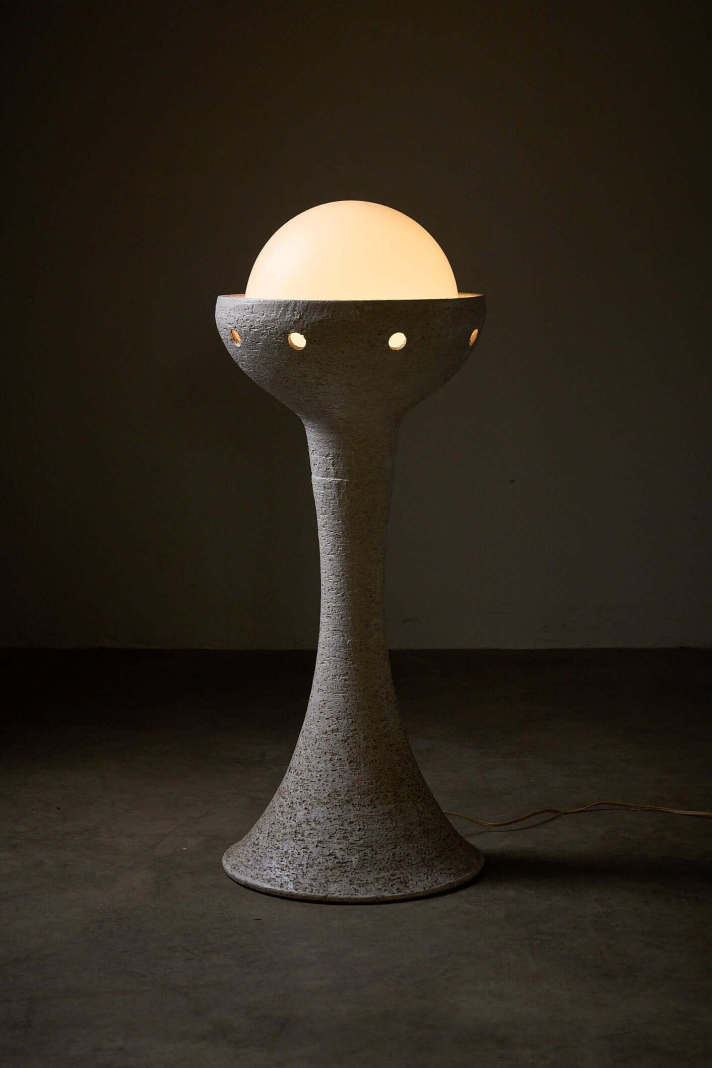 Natural ceramic floor lamp with glass sphere diffuser by BEGA, featuring a tall textured white finish and soft ambient lighting.