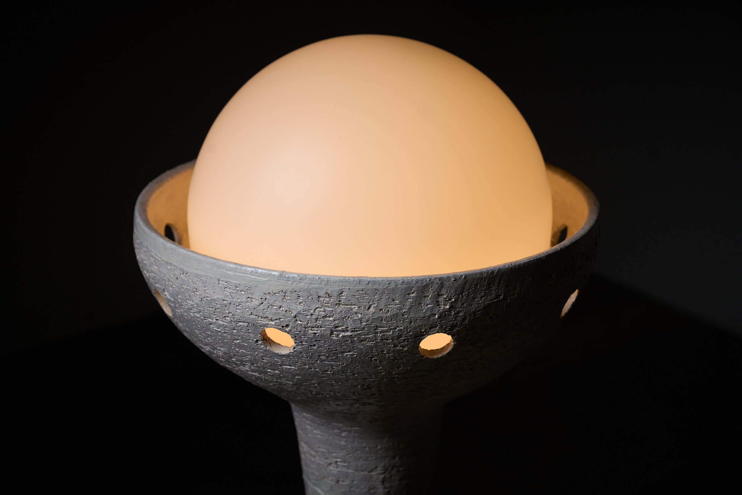 Close-up of natural ceramic floor lamp with glass sphere diffuser emitting soft ambient lighting