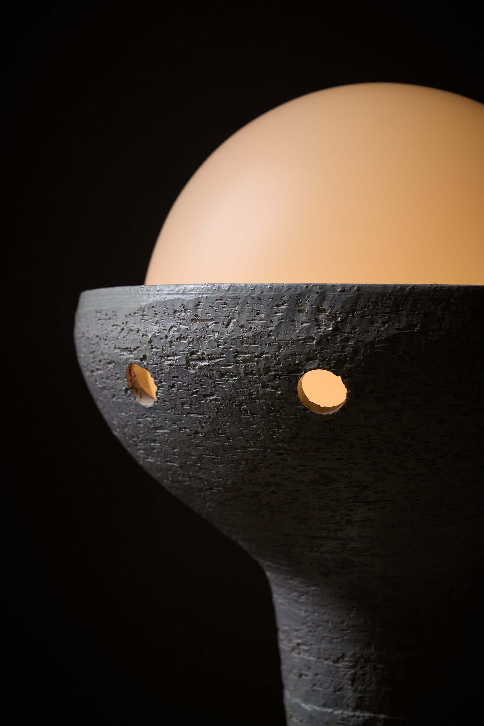 Close-up of natural ceramic floor lamp with glass sphere diffuser providing ambient lighting