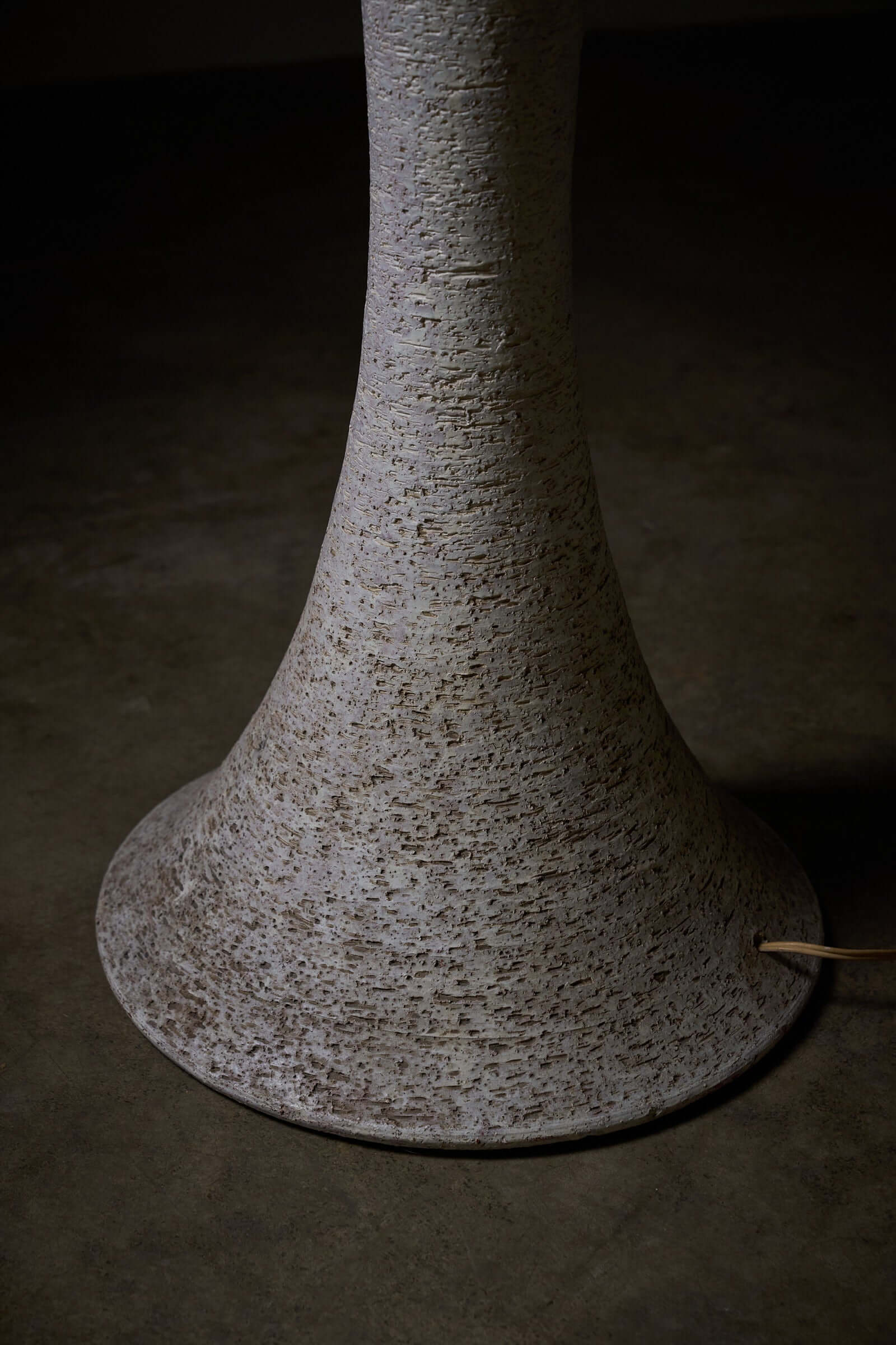 Base of BEGA natural ceramic floor lamp with textured white finish on dark background