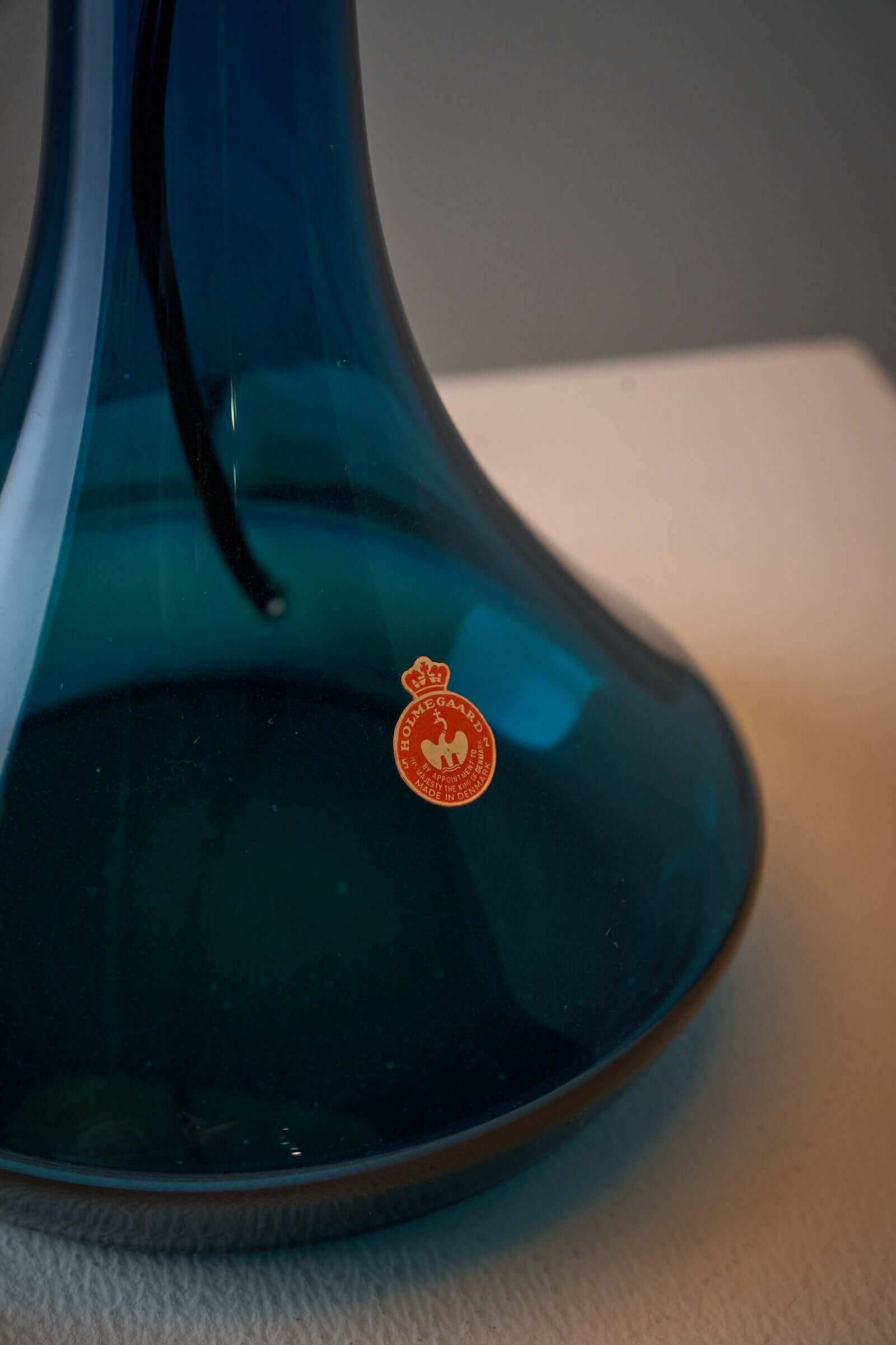 Close-up of the deep blue Holmegaard glass base featuring a vintage authenticity sticker from Fog & Mørup.