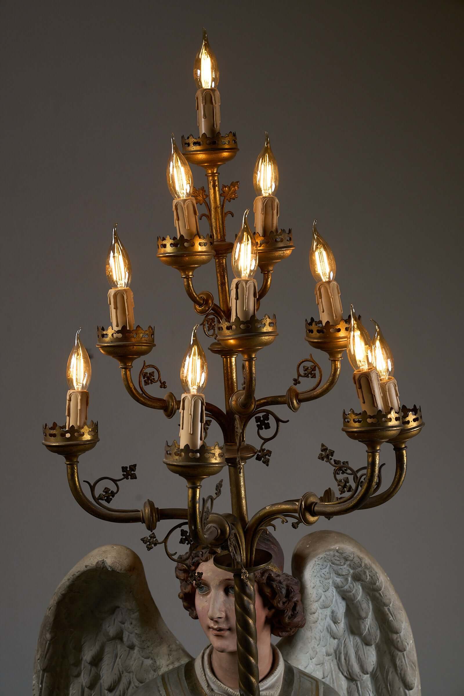 Antique 19th-century angel candle holder with ornate brass chandelier and electric bulbs