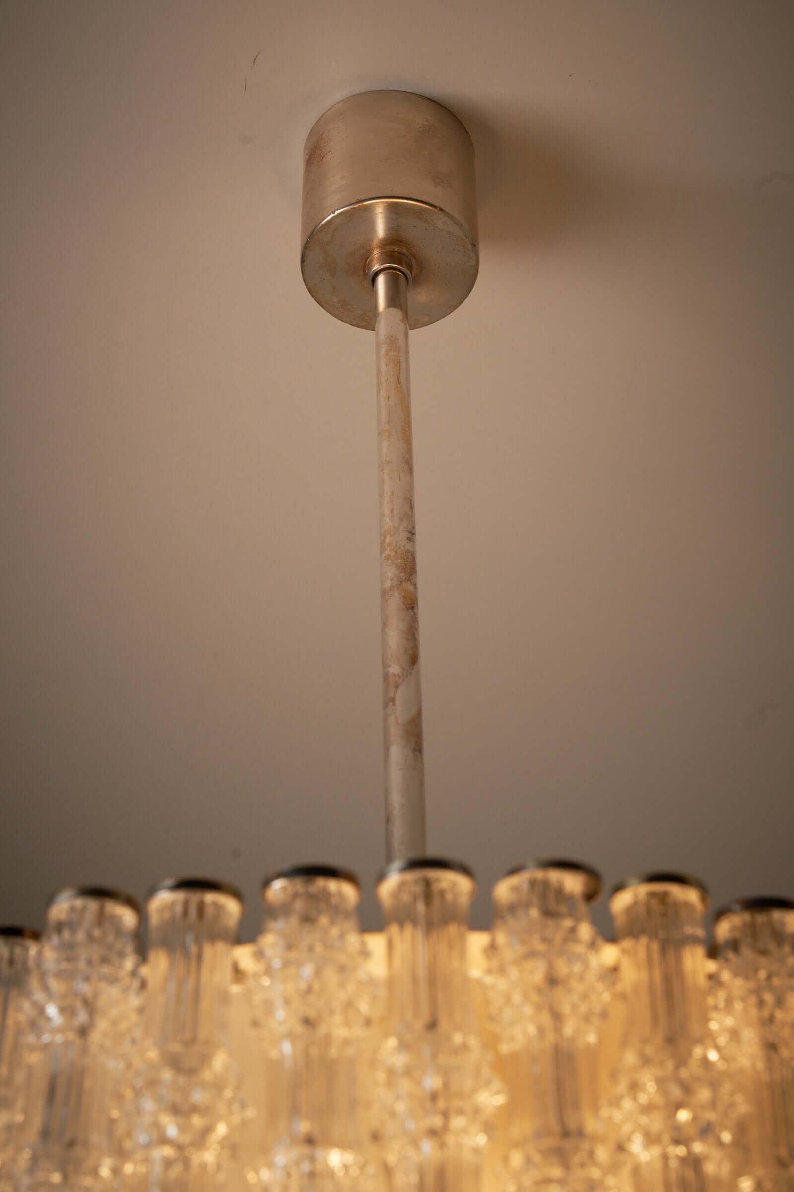 Close-up view of the ceiling mount and stem of the Kaiser Leuchten glass pendant lamp with nickel patina.