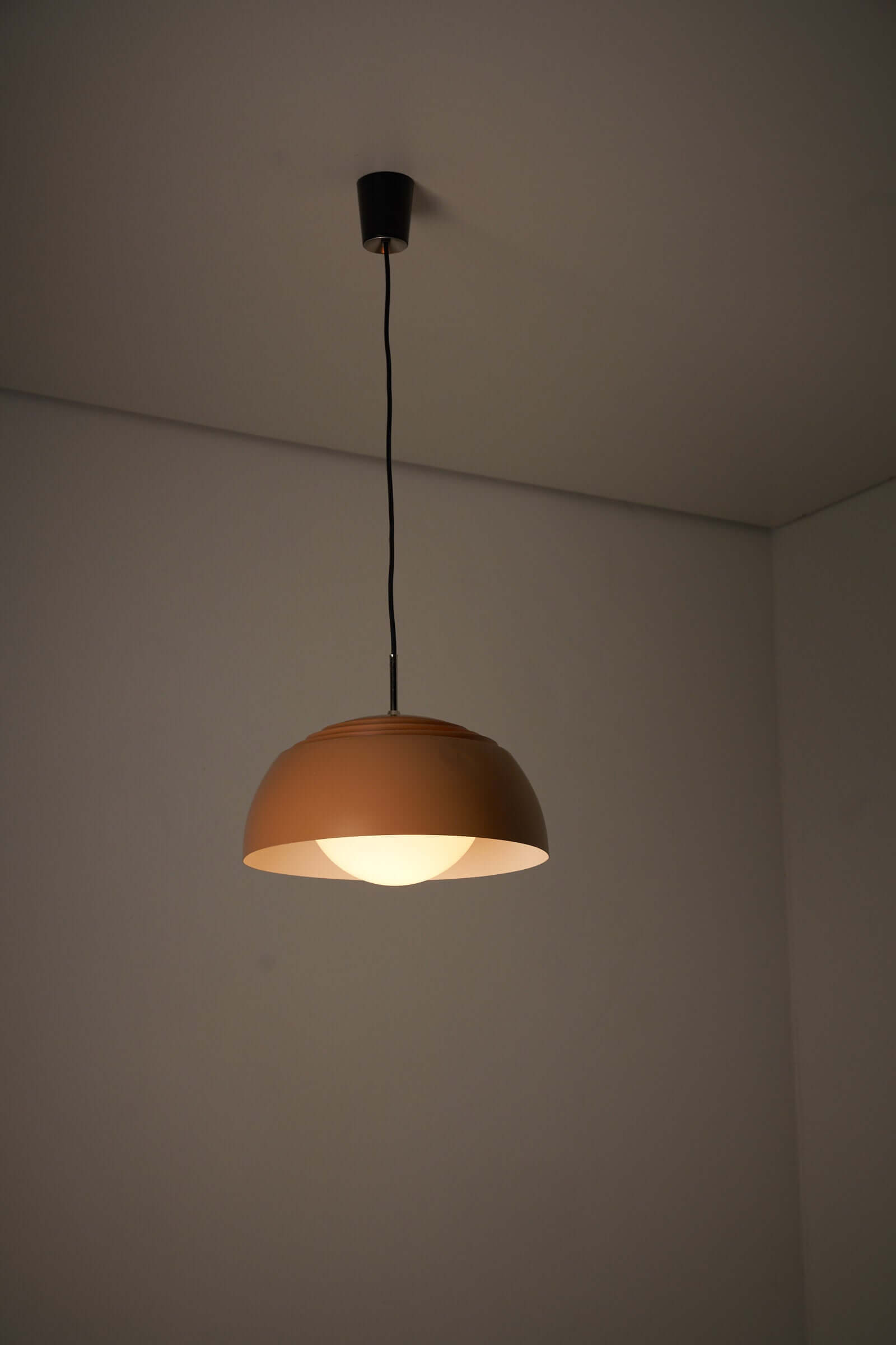 Orange dome pendant lamp by B+L Leuchten with opal glass diffuser, hanging from a ceiling in a minimalist setting.