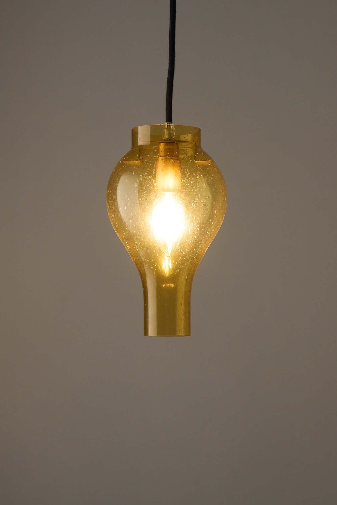 Elegant yellow glass pendant lamp with bubbles, casting a warm glow in contemporary interiors.