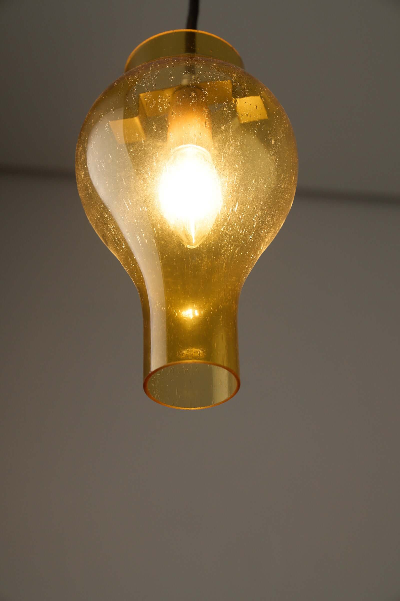 Elegant yellow glass pendant lamp with bubbles, casting a warm glow in a modern interior.