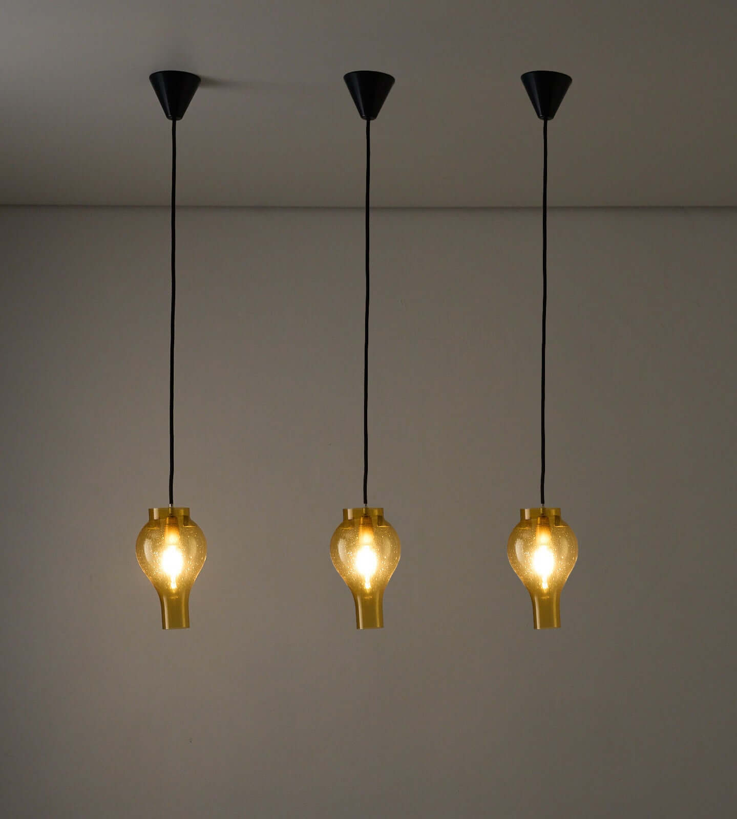 Elegant yellow glass pendant lamps with bubbles, hanging from a ceiling, illuminating a modern interior space.