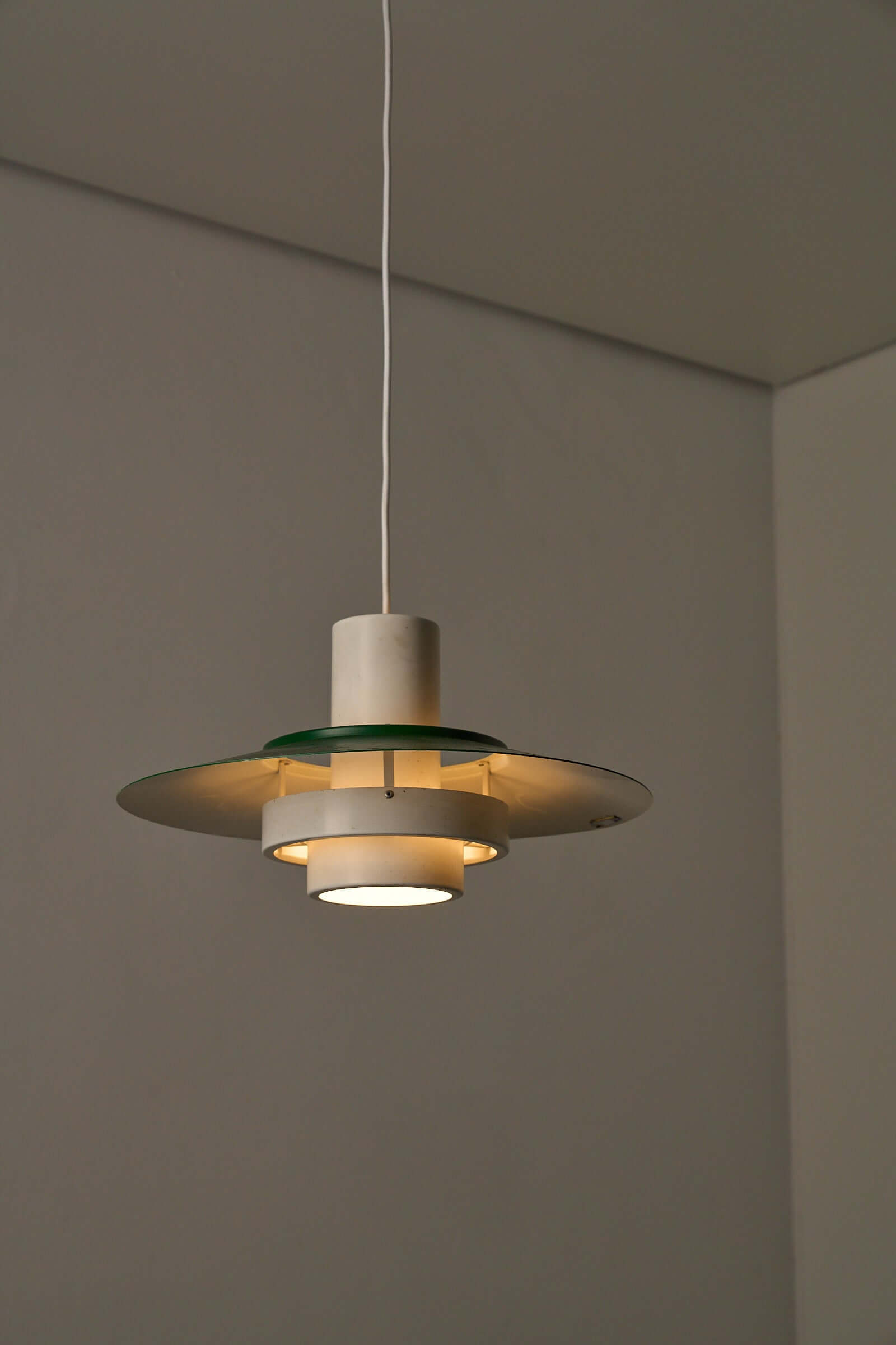 Vintage Falcon pendant light by Andreas Hansen, showcasing green lacquered shade and layered diffusers.