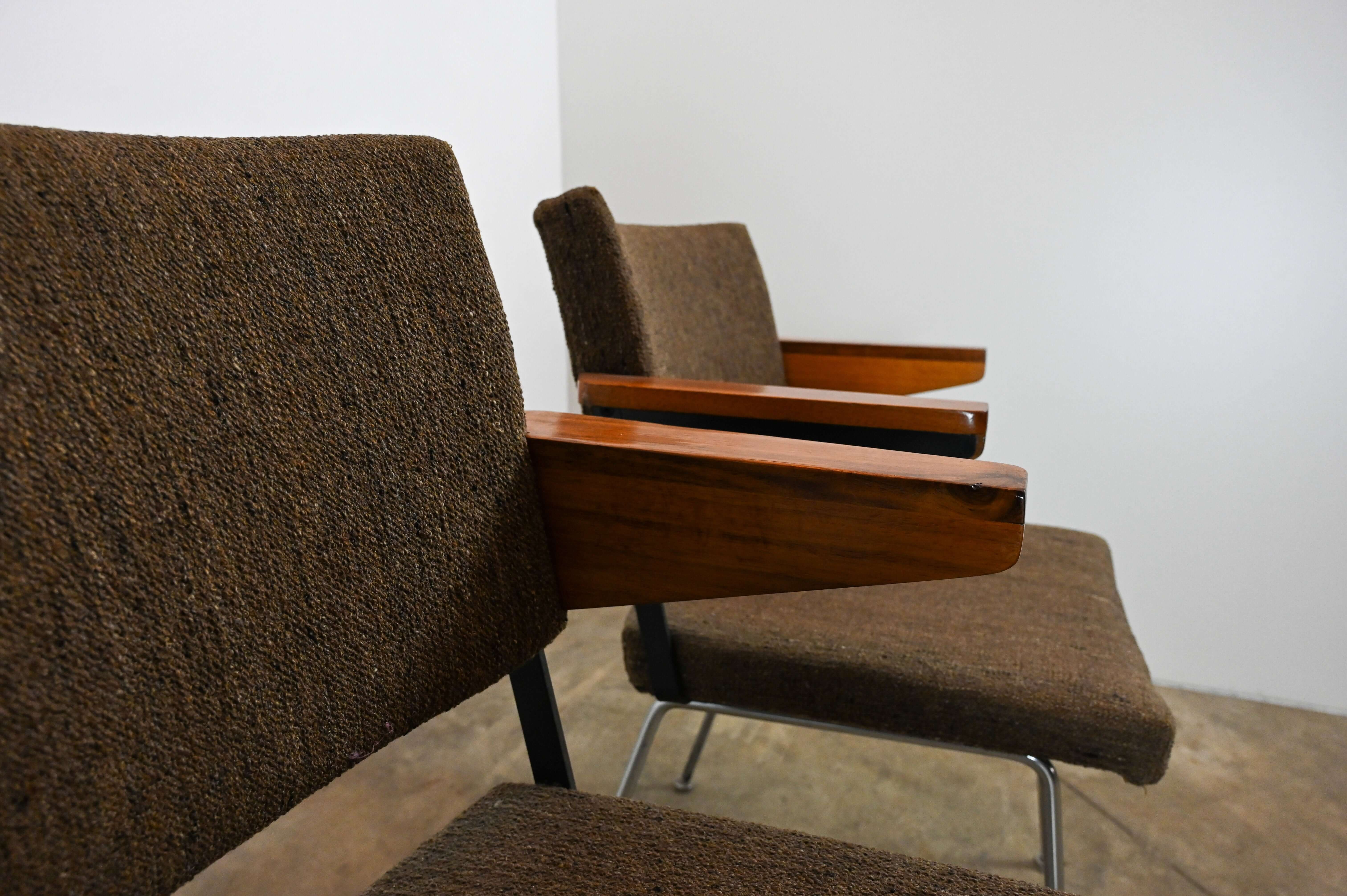 Close-up of Gispen "L11" armchairs by A.R. Cordemeyer with wooden armrests and brown textured fabric upholstery.