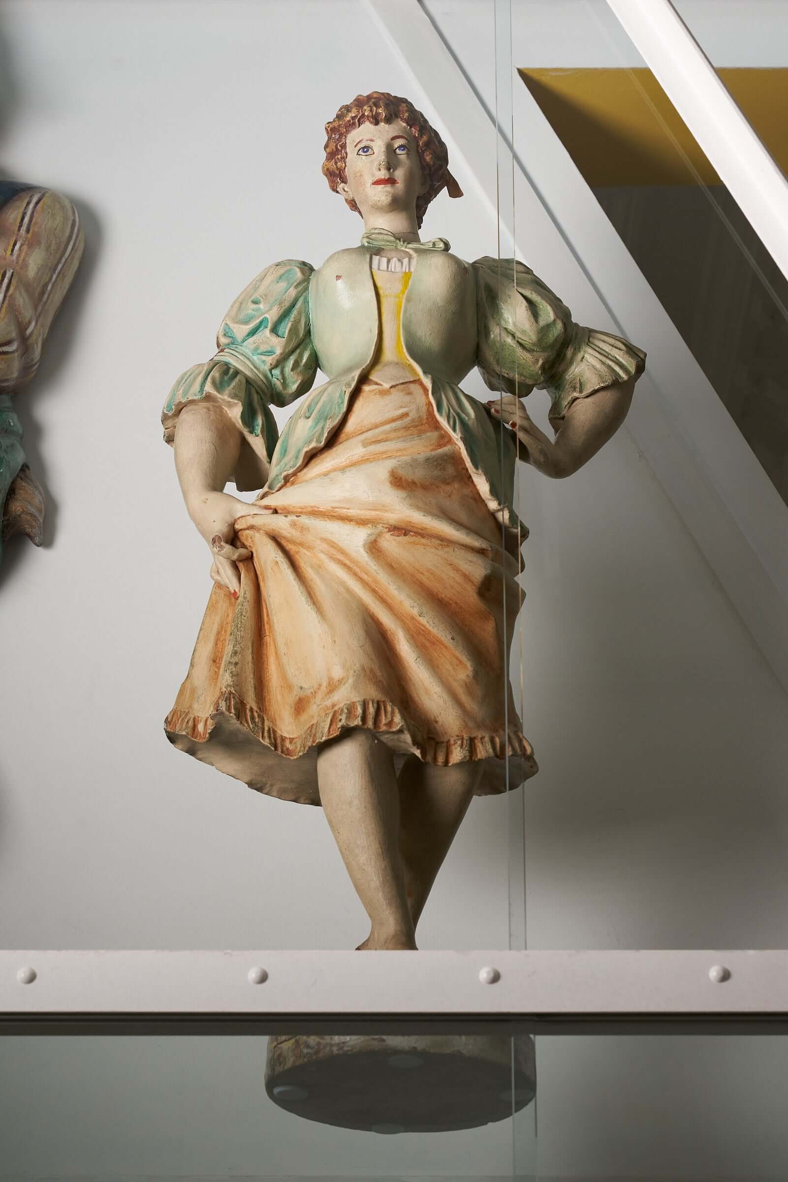 Antique hand-carved wooden carousel figure of a woman in a green and orange dress, part of an antique carousel figure collection.