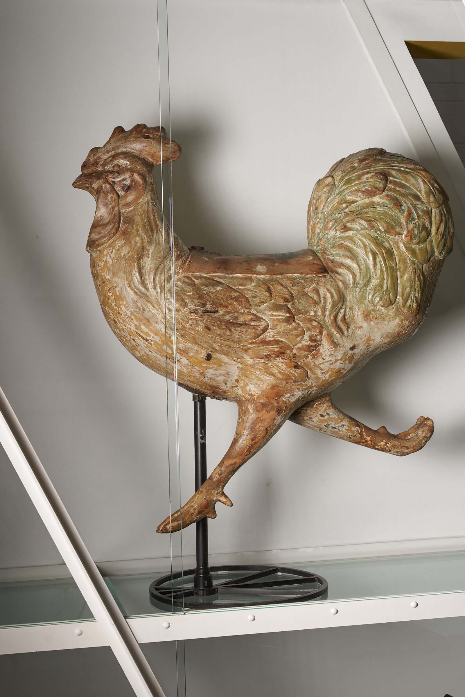 Hand-carved antique wooden carousel rooster figure on a display stand.