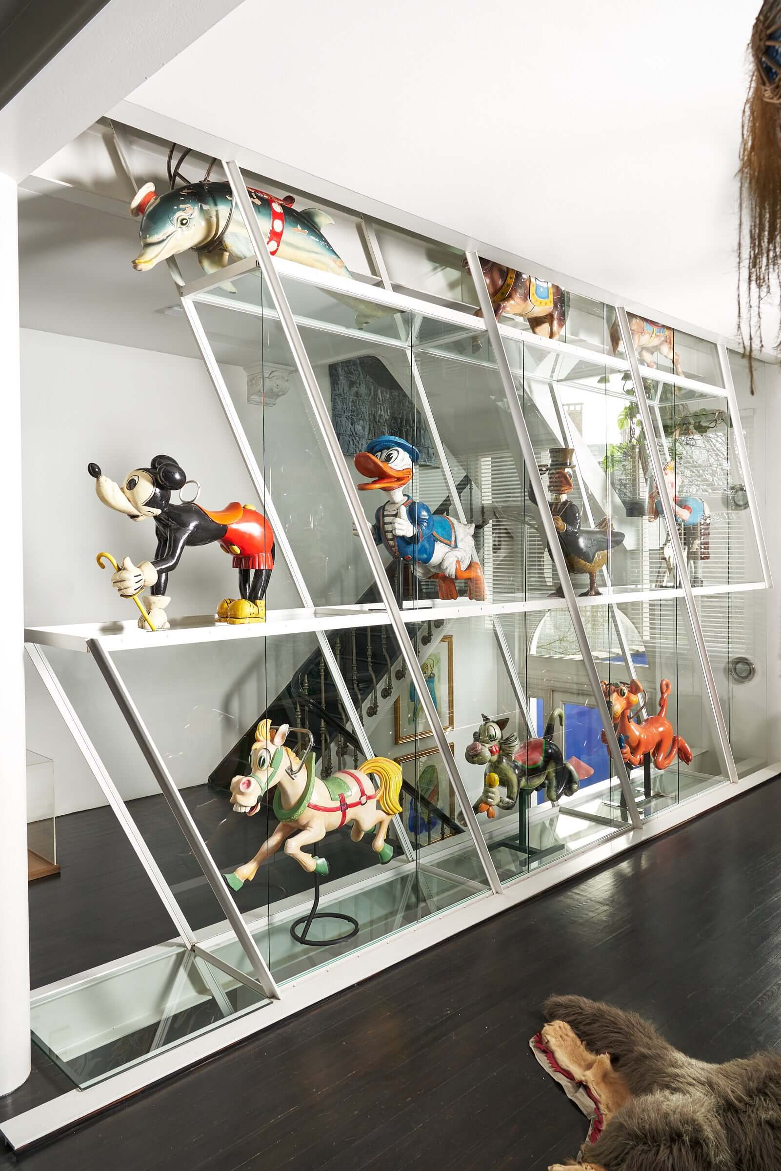 Antique wooden carousel figures collection featuring Mickey Mouse, Donald Duck, and other beloved characters on display in a modern setting