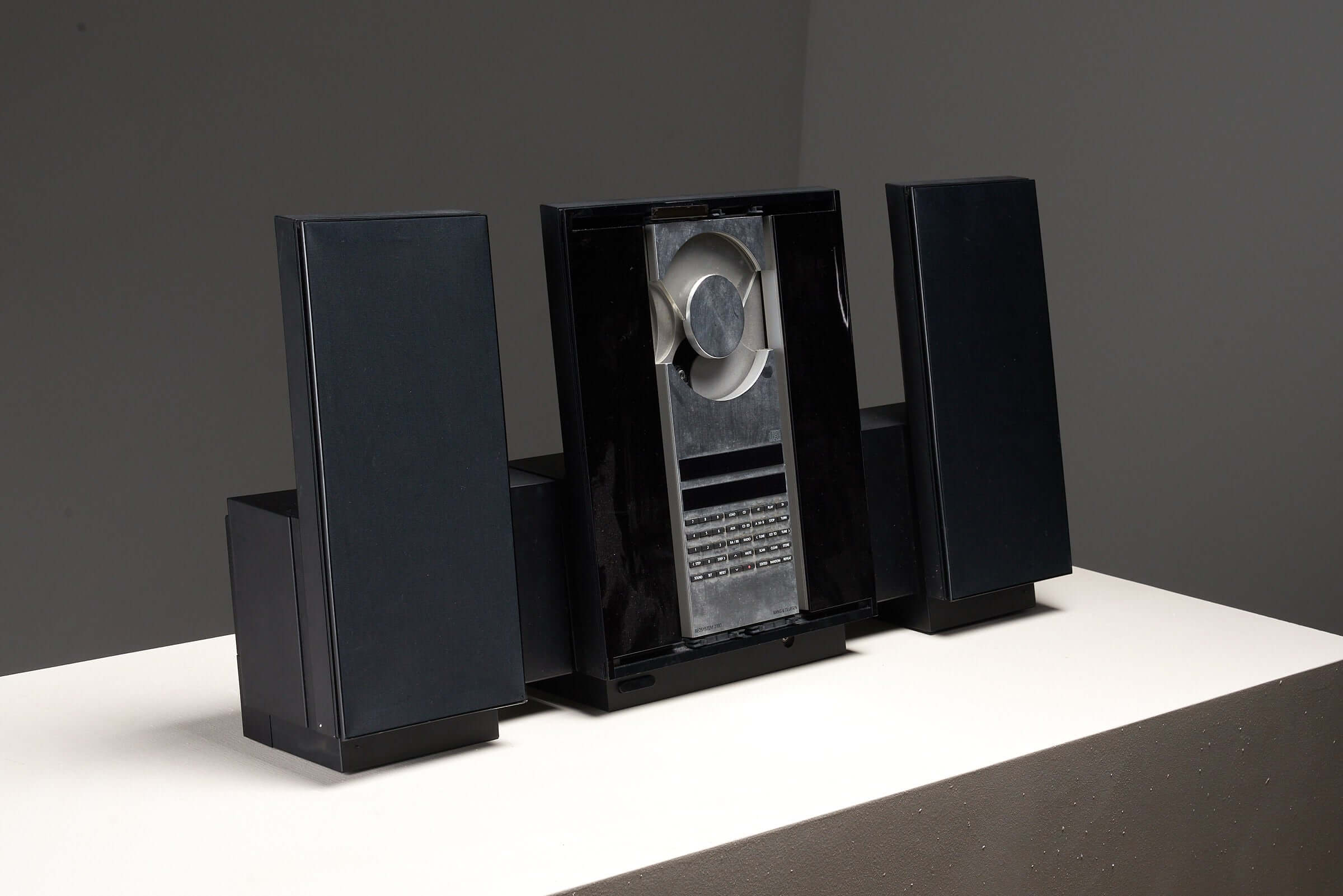 Bang & Olufsen BeoSystem 2300, a sleek 1990s audio system with sliding glass panel, black finish, and minimalist Danish design.