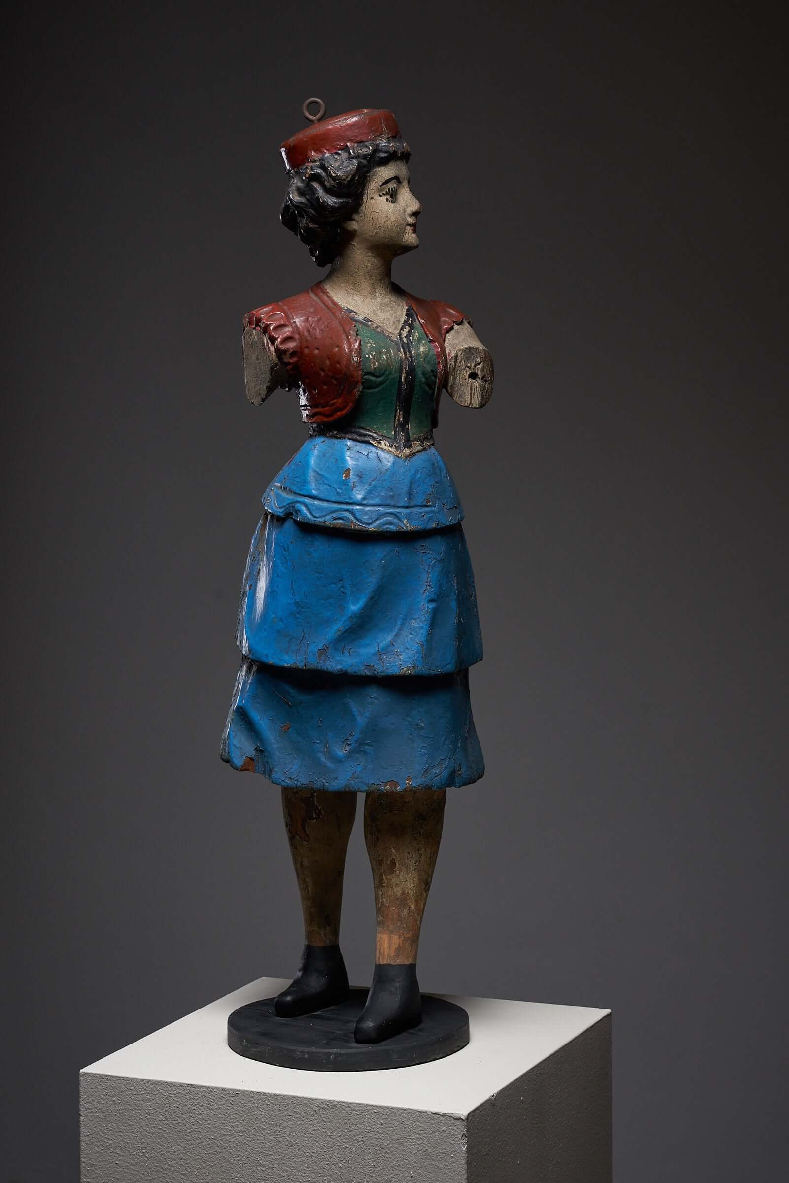 Hand-painted antique carousel lady figure in a blue skirt, early 20th-century wooden sculpture with intricate detailing on display.