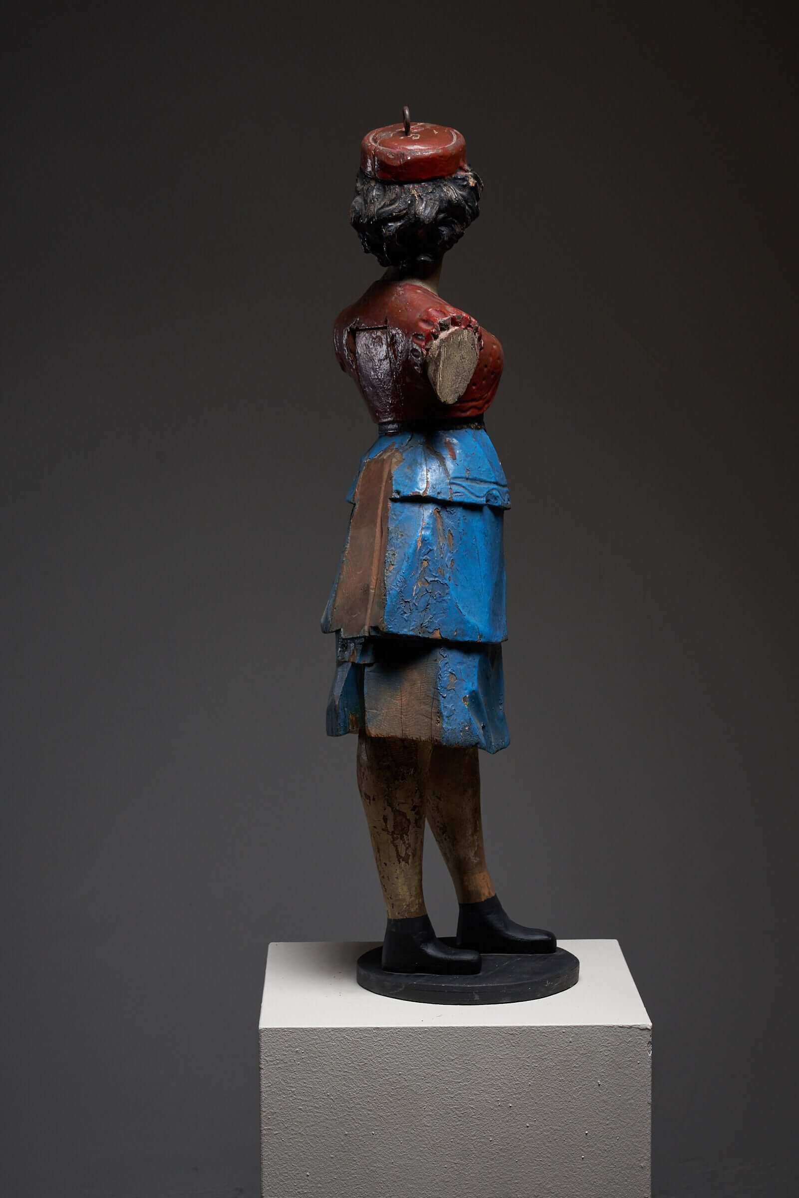 Hand-painted antique wooden carousel figure of a lady in a blue skirt on a pedestal, showcasing early 20th-century craftsmanship.