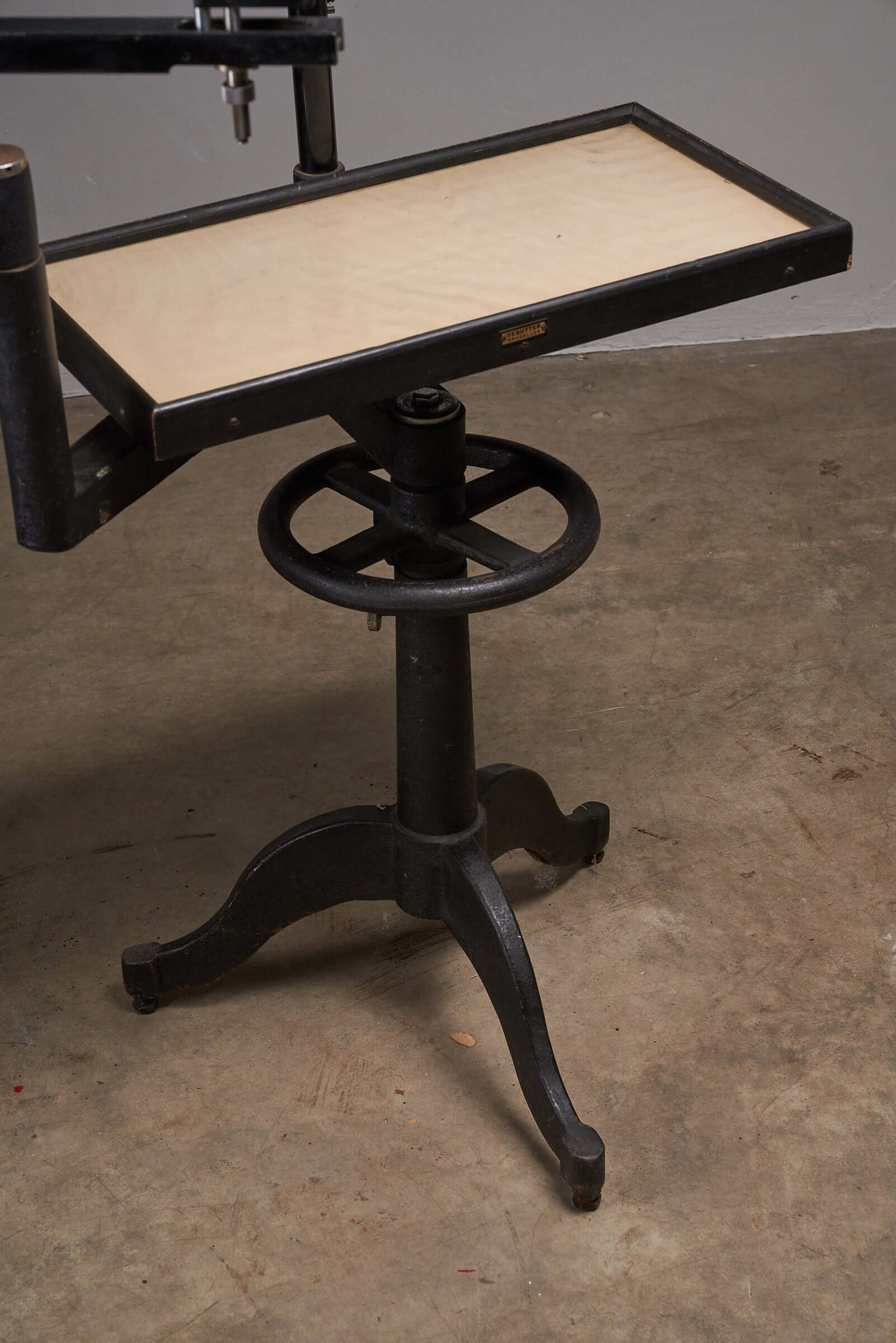 Vintage black optometry examination table from the early 20th century with adjustable mechanism in industrial design aesthetic.