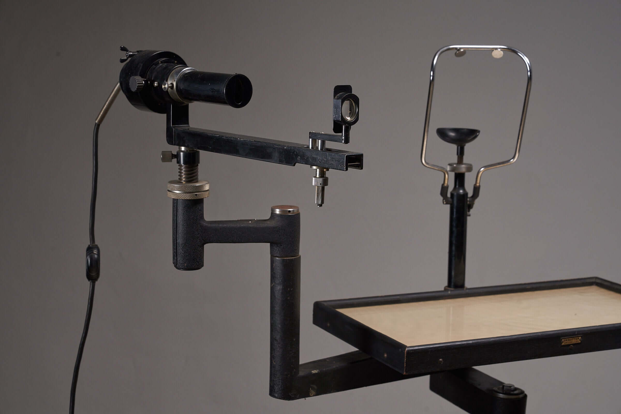 Vintage black optometry examination table from early 20th century, showcasing industrial design and adjustable mechanisms.