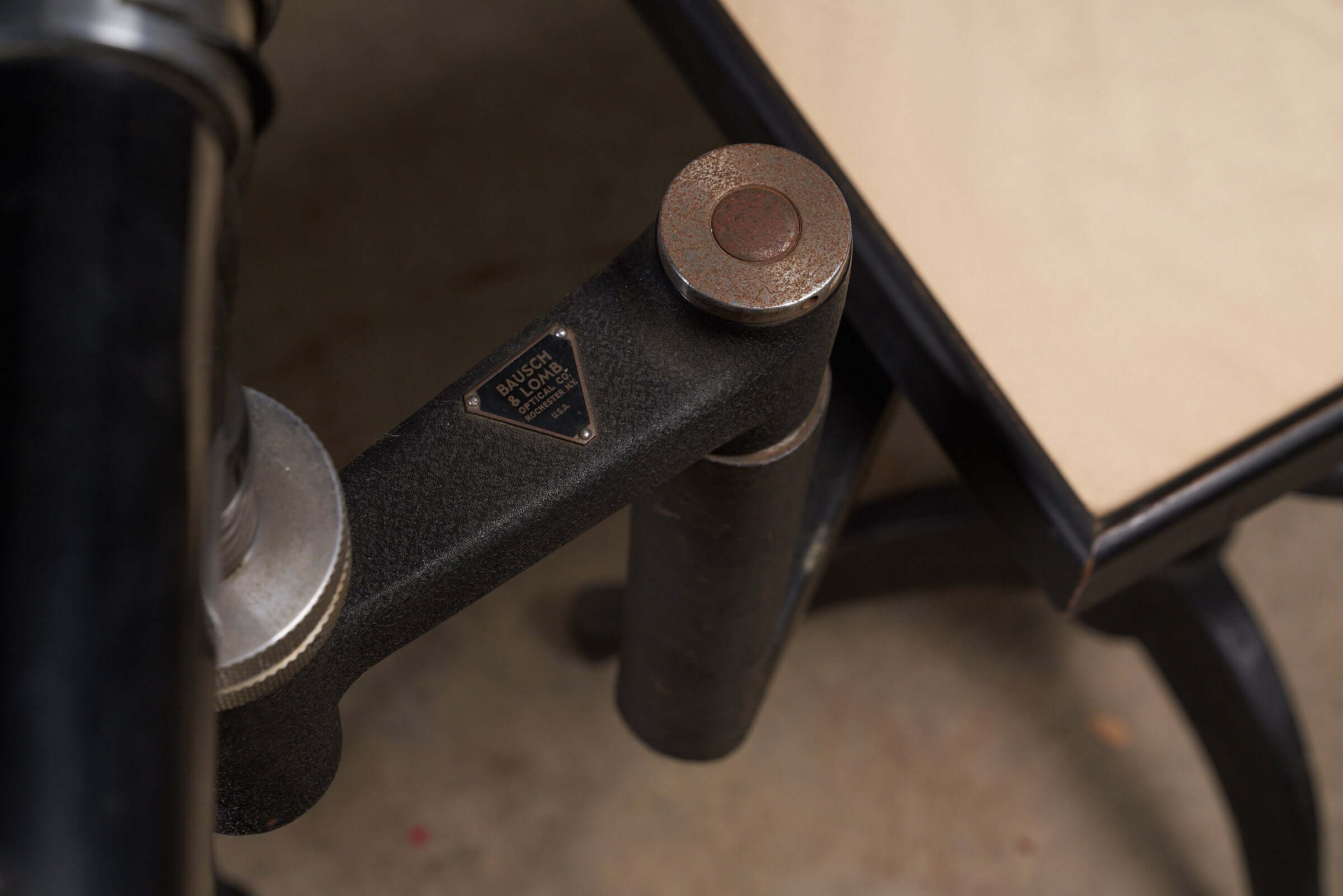 Close-up of the adjustable mechanism on a vintage black optometry examination table from the early 20th century.