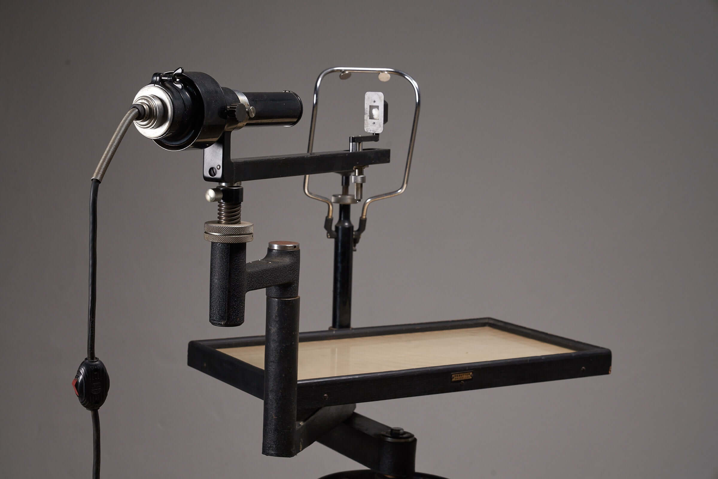 Vintage black optometry examination table from early 20th century with adjustable mechanism and industrial design aesthetic