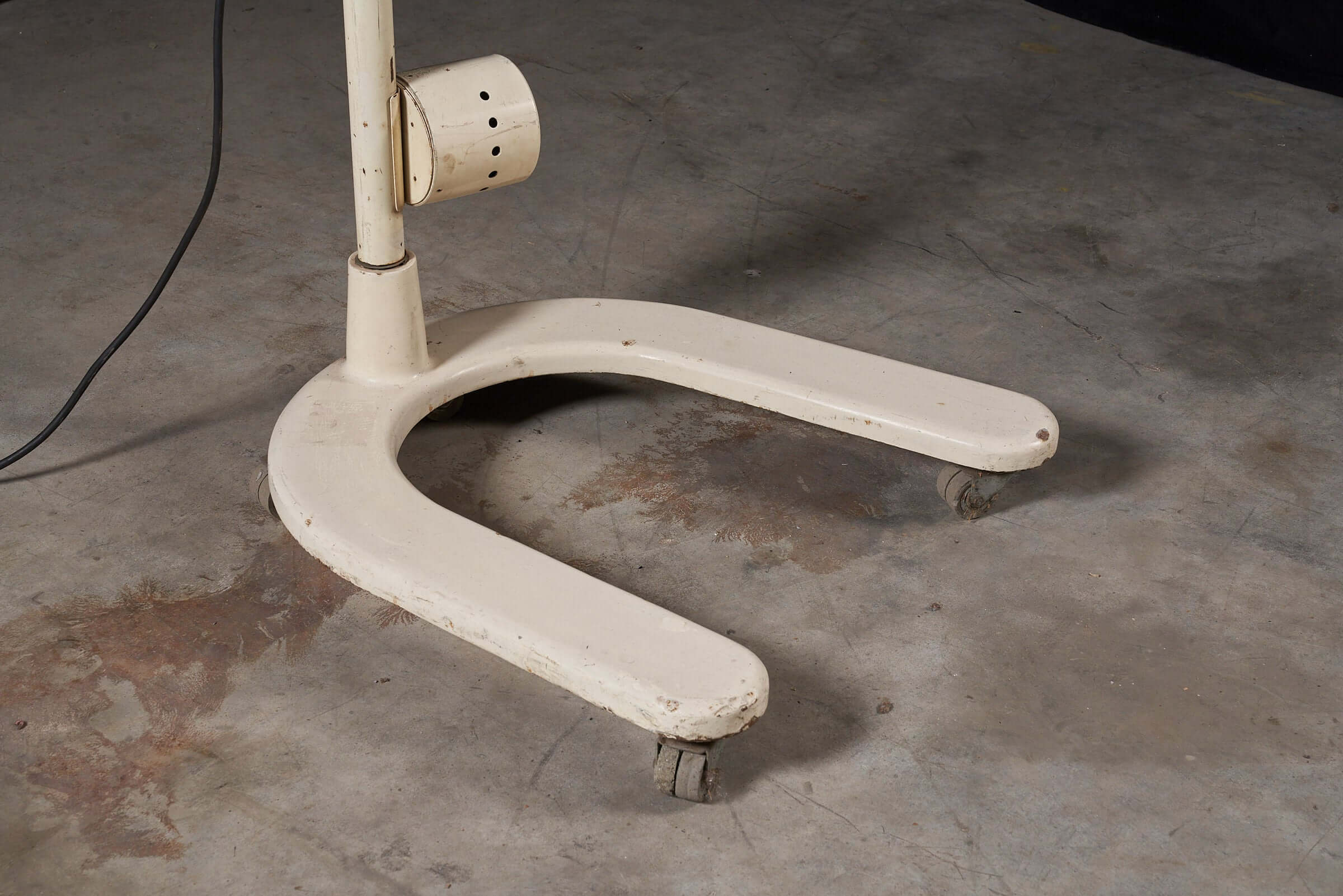 Adjustable stand on wheels from vintage cream medical lamp by Chromophare on concrete floor.