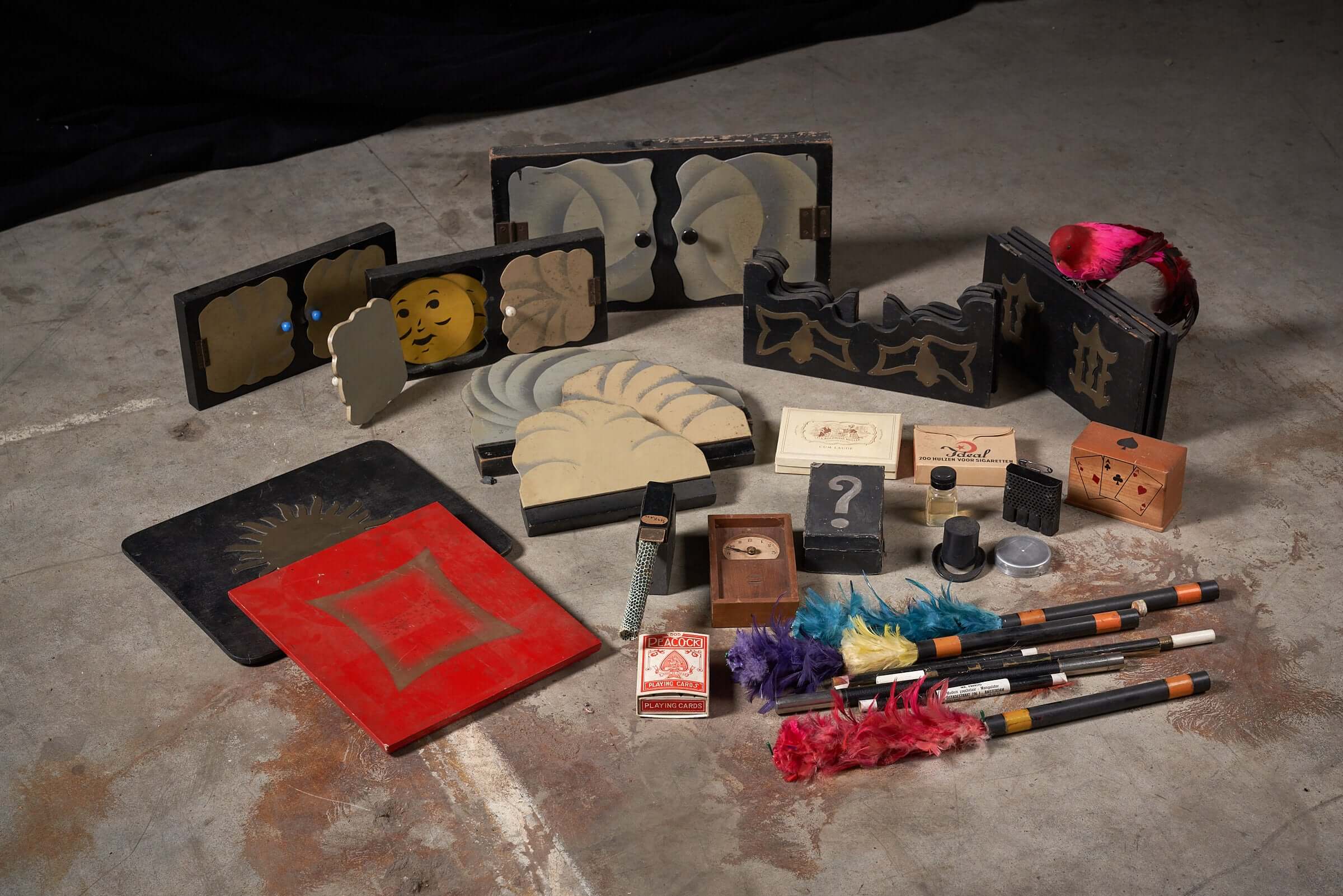 Vintage magician's tool collection with assorted magic props and accessories displayed on a concrete floor.