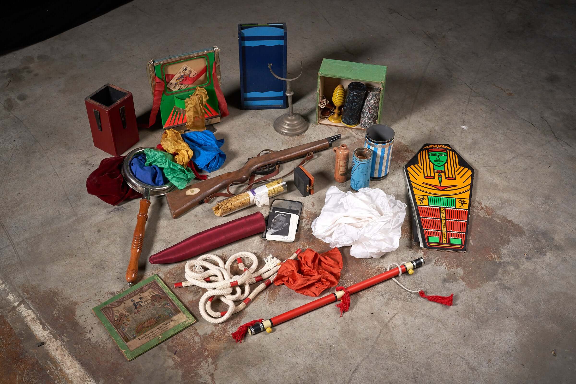 Vintage magician’s tool collection with assorted magic props including wands, hats, scarves, and classic accessories displayed on the floor.