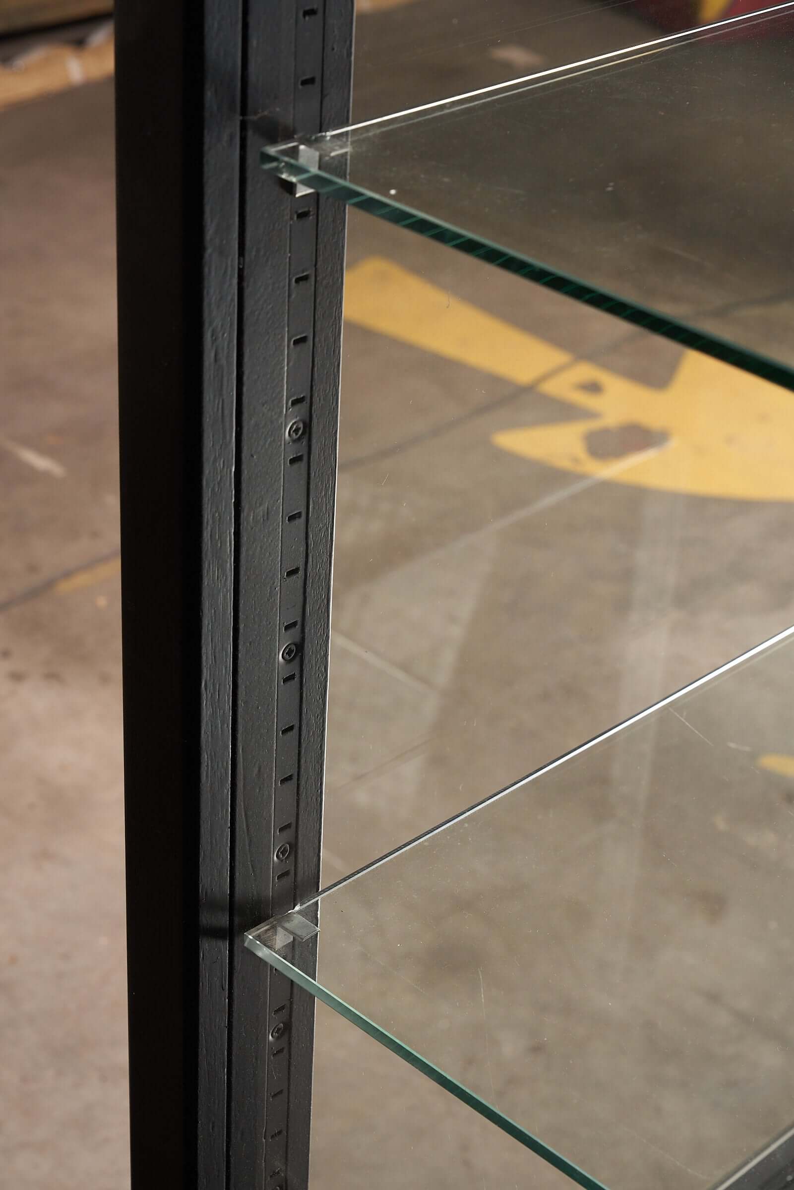 Close-up view of the vintage black display cabinet with glass shelves and sturdy frame for showcasing collections.