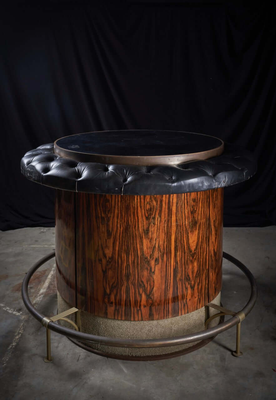 Vintage rosewood and black leather bar table with tufted edge and metal base, mid-century circular design showcasing retro charm