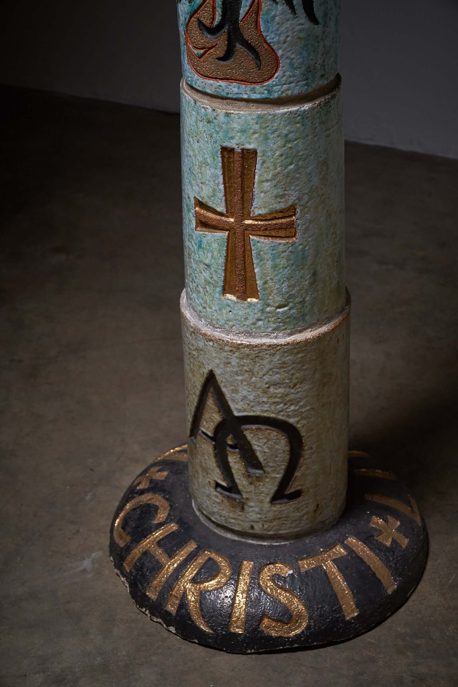 Ceramic totem with Christian symbols, including a cross and Alpha Omega signs, multicolored religious decorative piece.