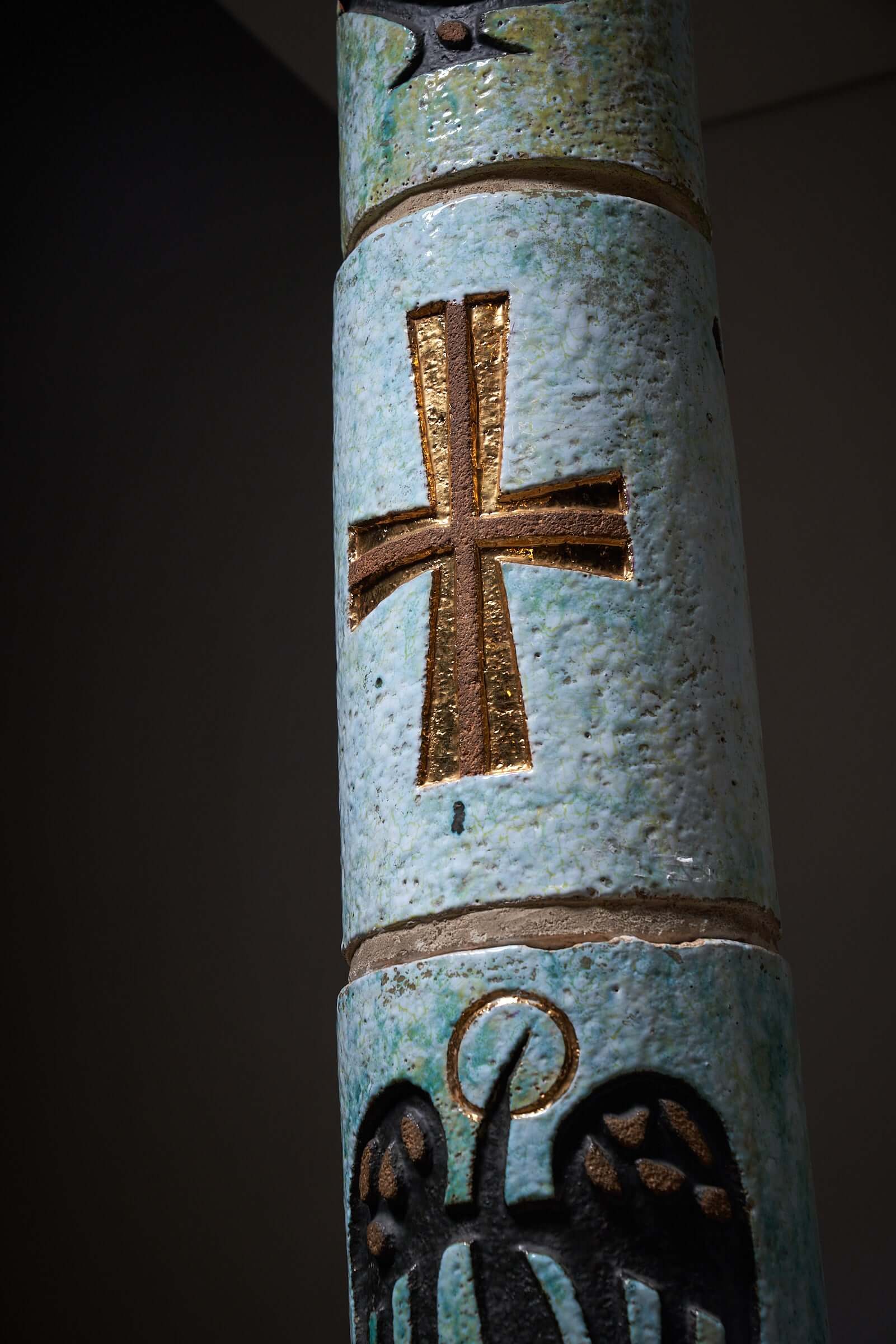 Ceramic totem with golden cross and Christian symbols, multicolored religious decorative item.