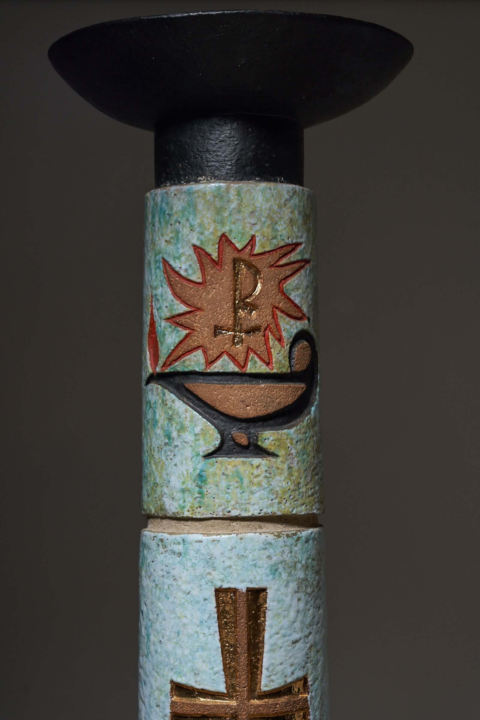 Ceramic totem with multicolored Christian symbols including a cross and Holy Spirit depiction