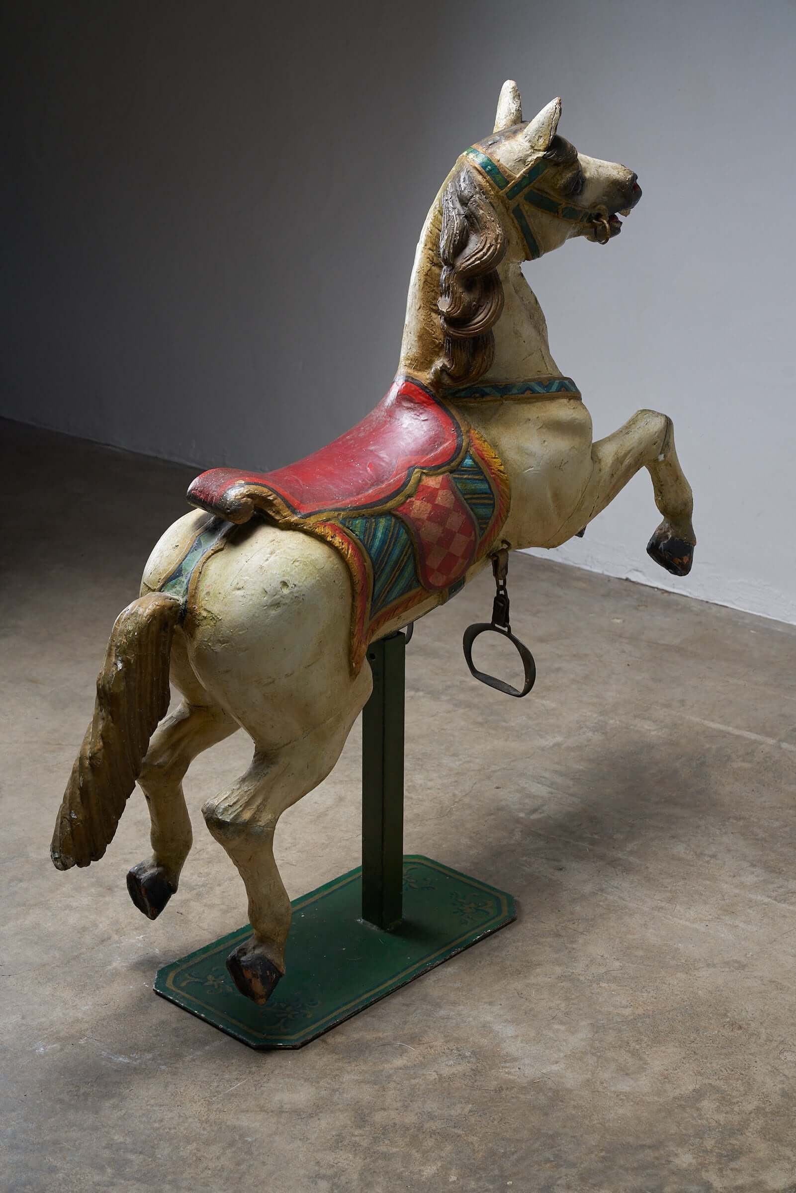 Antique hand-painted wooden carousel horse with red saddle rearing up, multicolored design, vintage fairground decor